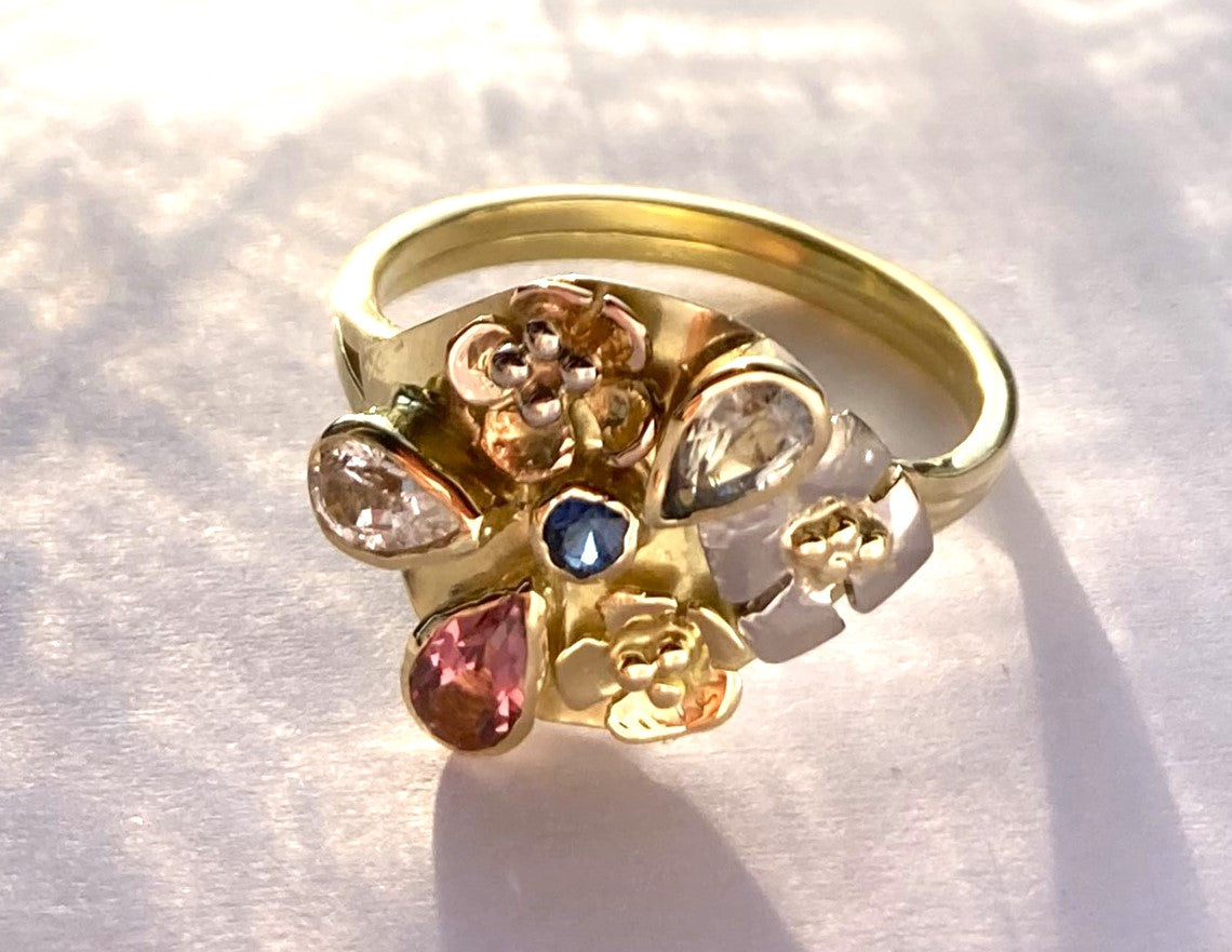 artisan flower and sapphire yellow gold cocktail ring, on mottled background