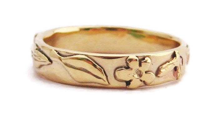 18ct yellow gold unisex wedding band with daisy and leaf details around the ring, on white background