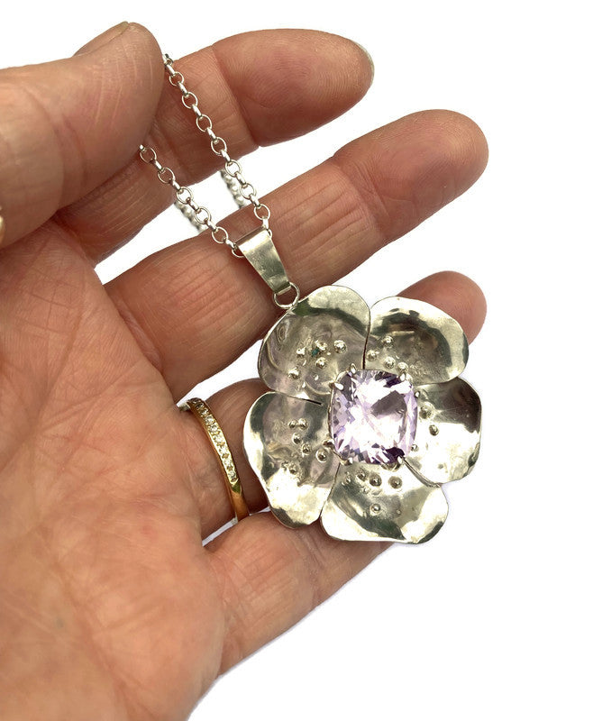 statement floral pendant set with big purple amethyst, held on fingers