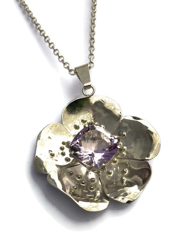 five petaled flower silver pendant with big purple center stone on white background