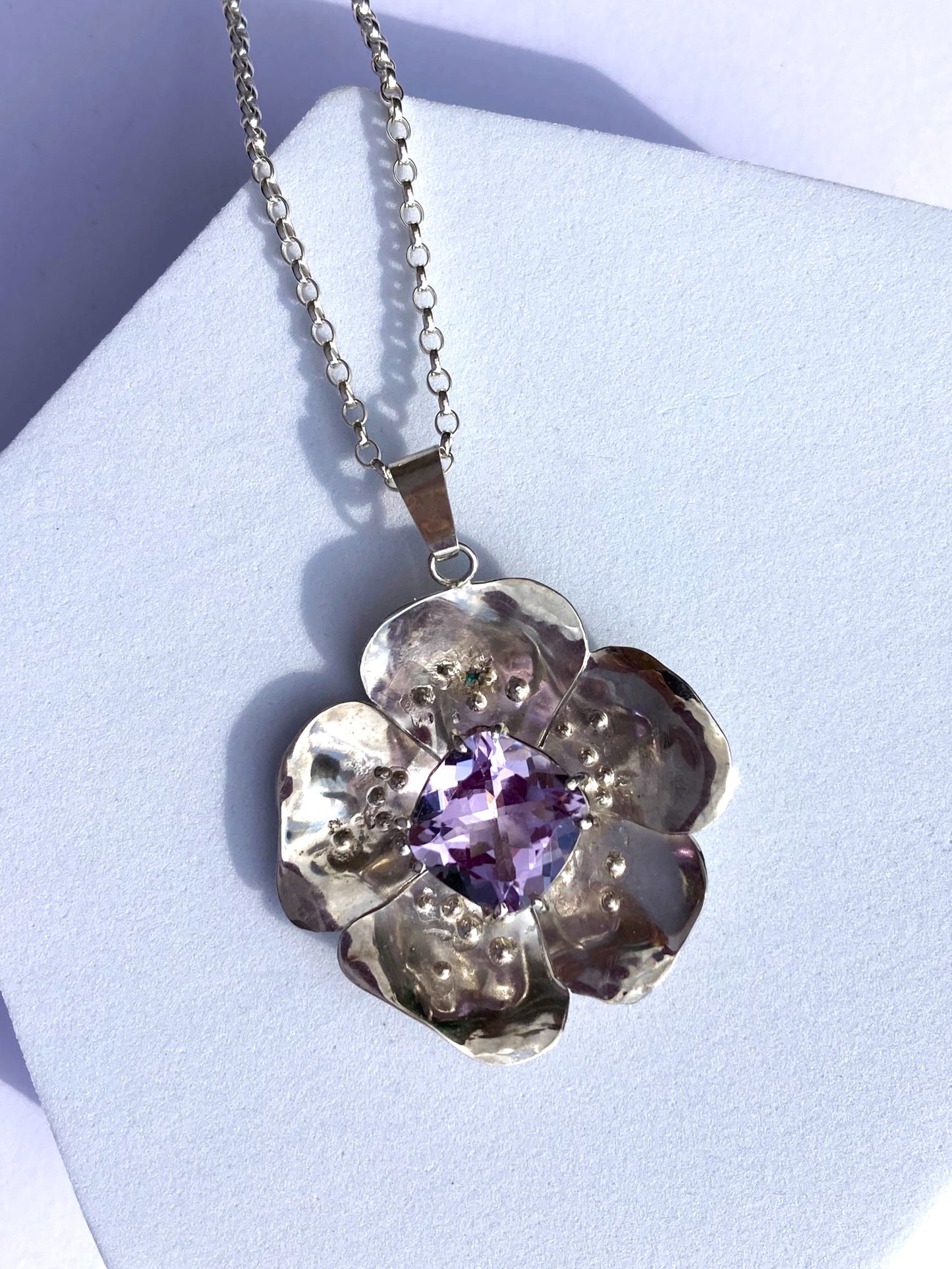 large flower pendant with big purple gemstone on grey background
