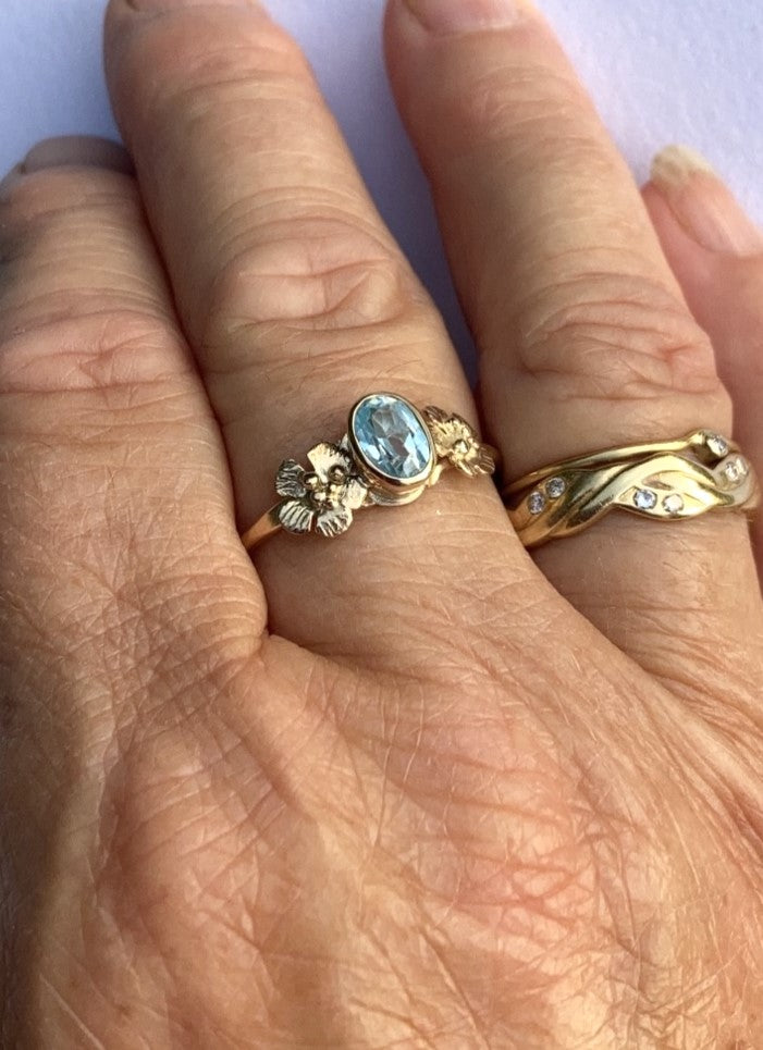 pale blue oval gemstone gold ring with flowers , worn on hand