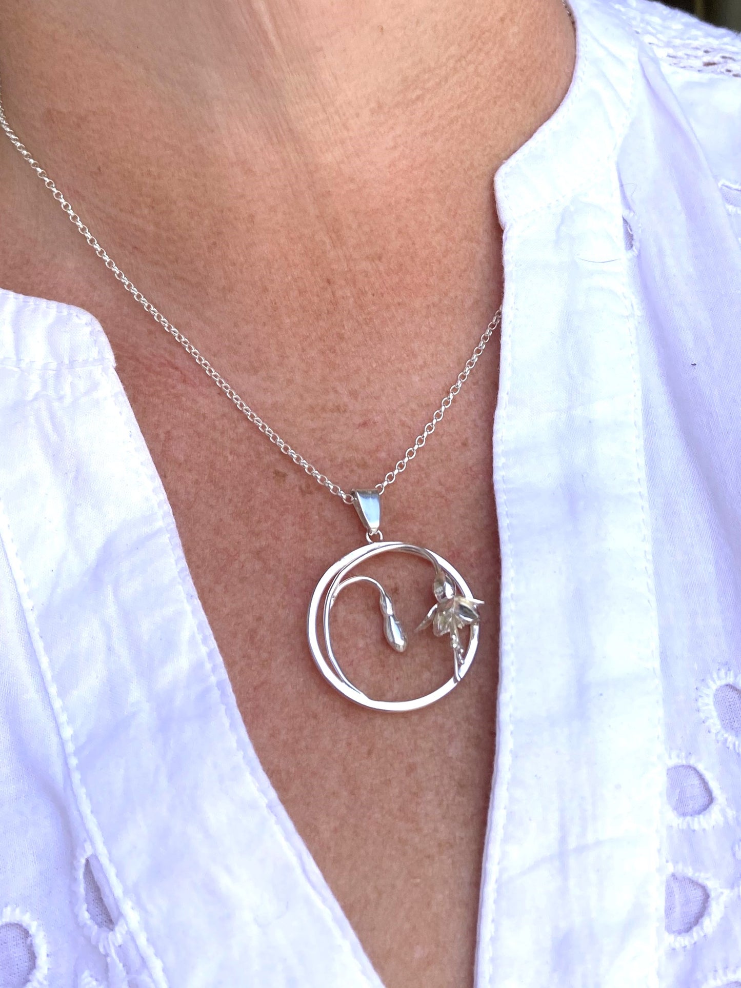 silver fuchsia pendant on neck with white shirt