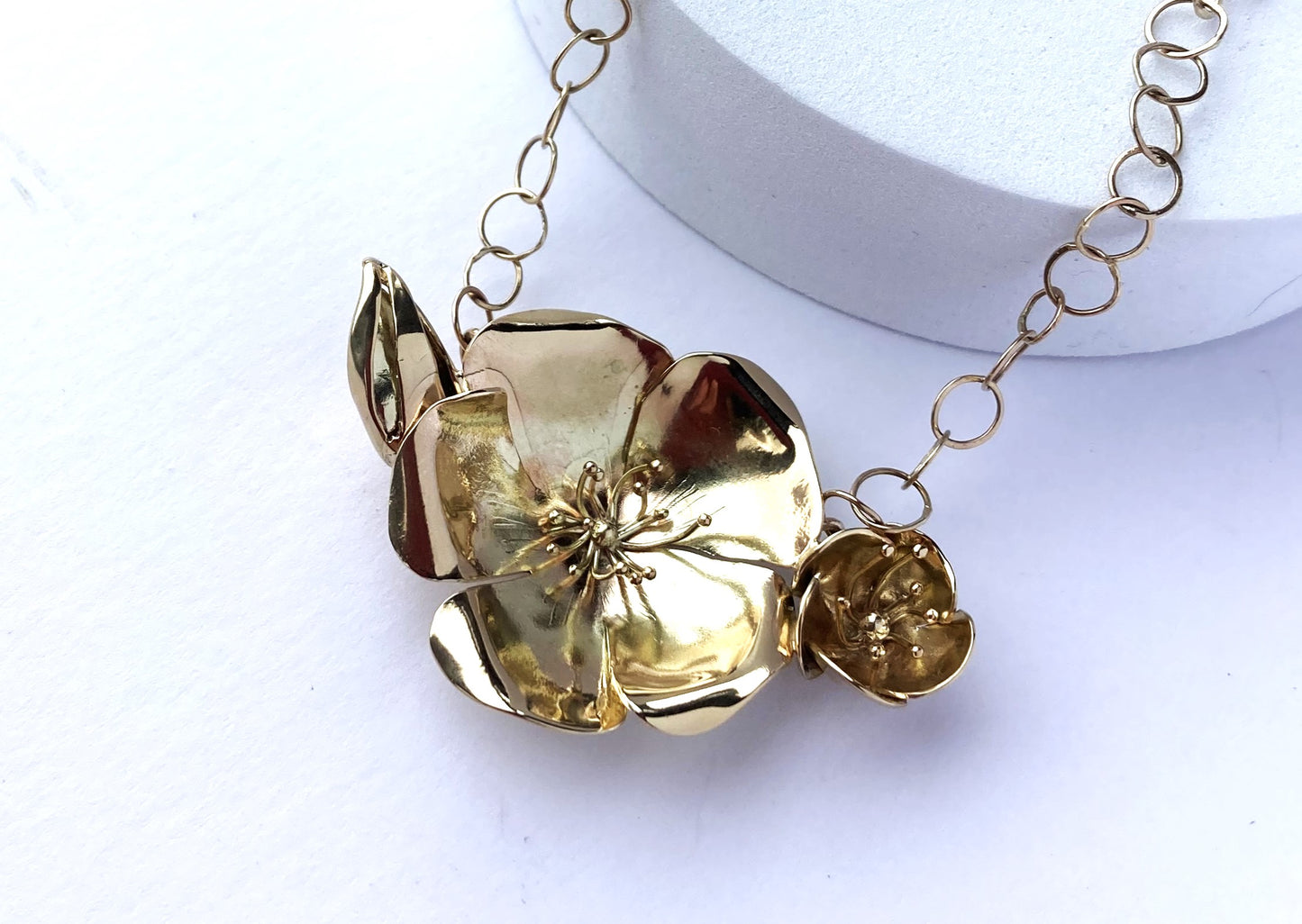 solid gold hand forged botanic wild rose statement necklace by Kim-Styles-Jewellery, on white background and plinth