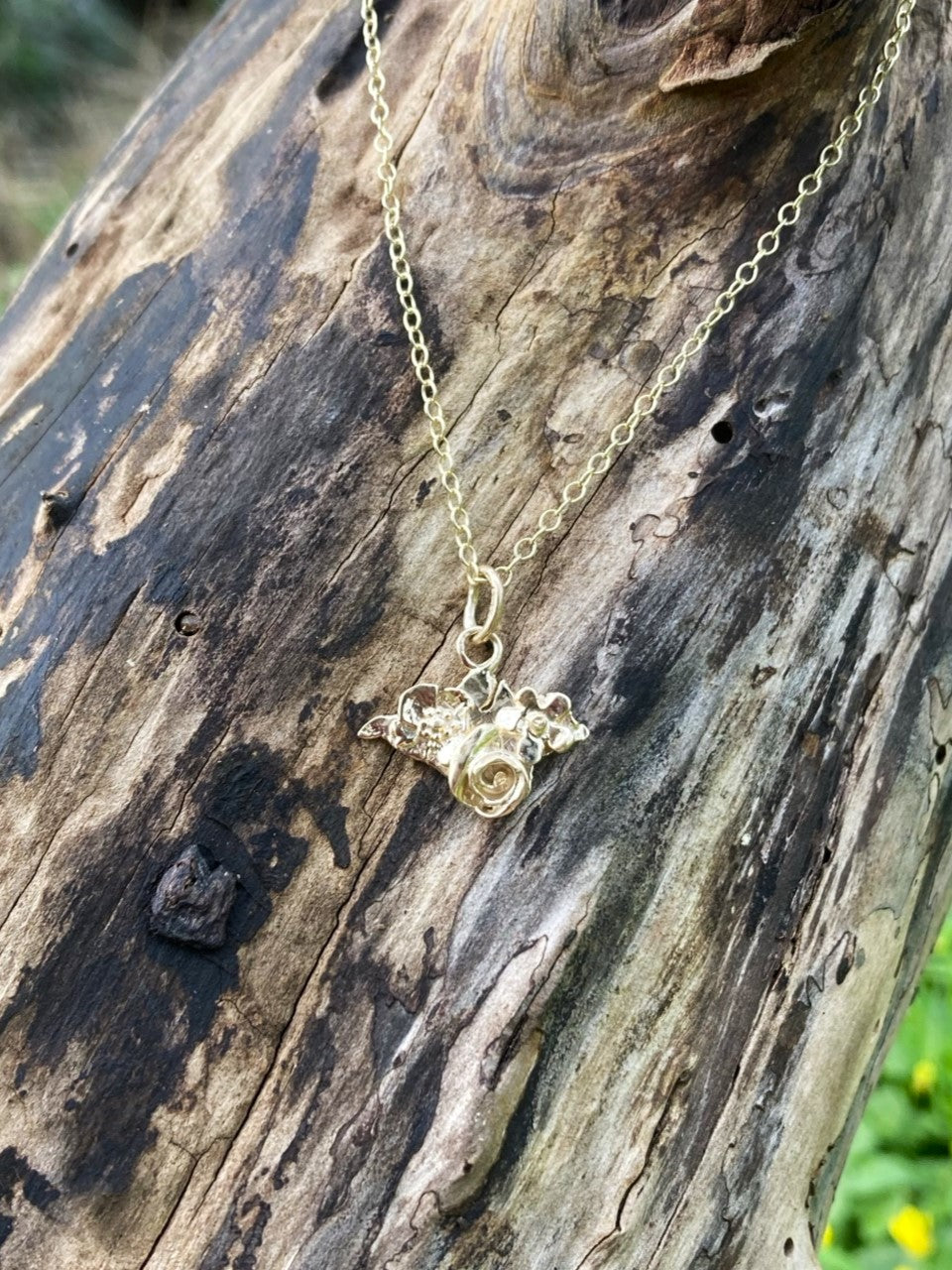 gold floral pendant in shape of Isle of Wight silhouette on tree background