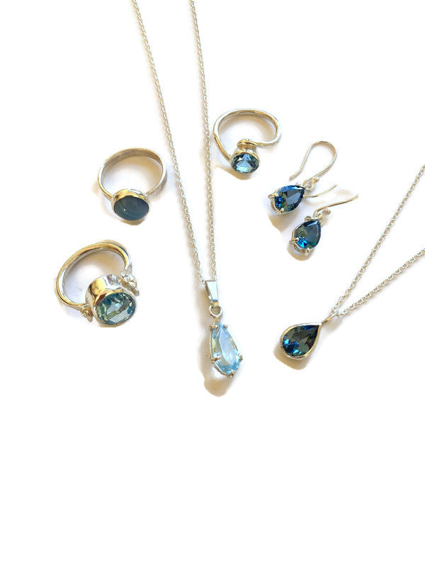 Kim Styles Jewellery set with rings, necklaces, and earrings featuring blue topaz gemstones on a white background