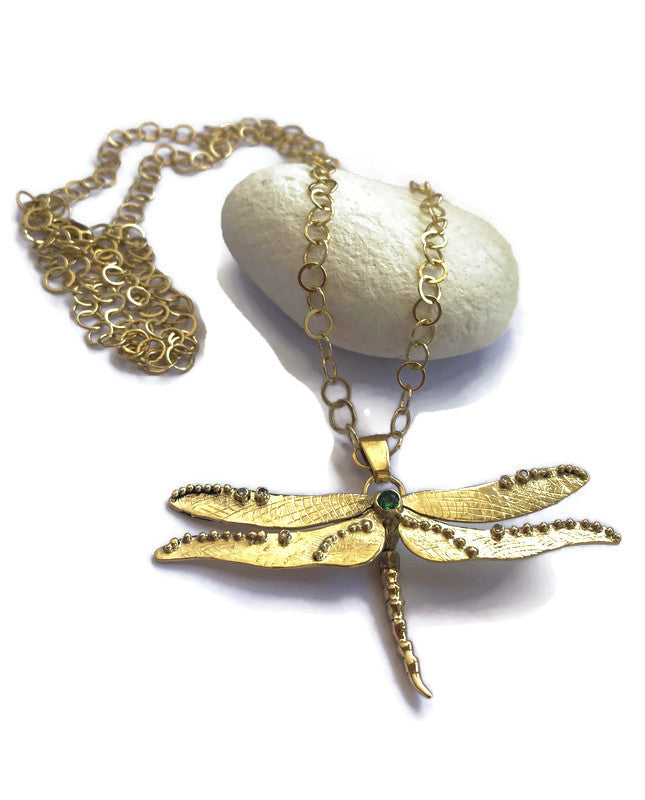 Gold dragonfly necklace on a white background