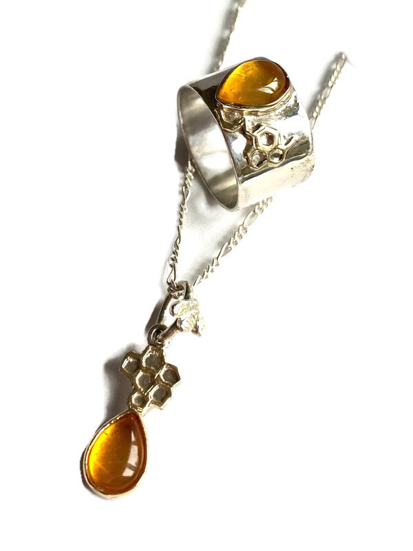 Silver necklace with gold set amber teardrop pendant with gold honeycomb detail and matching ring, on white background