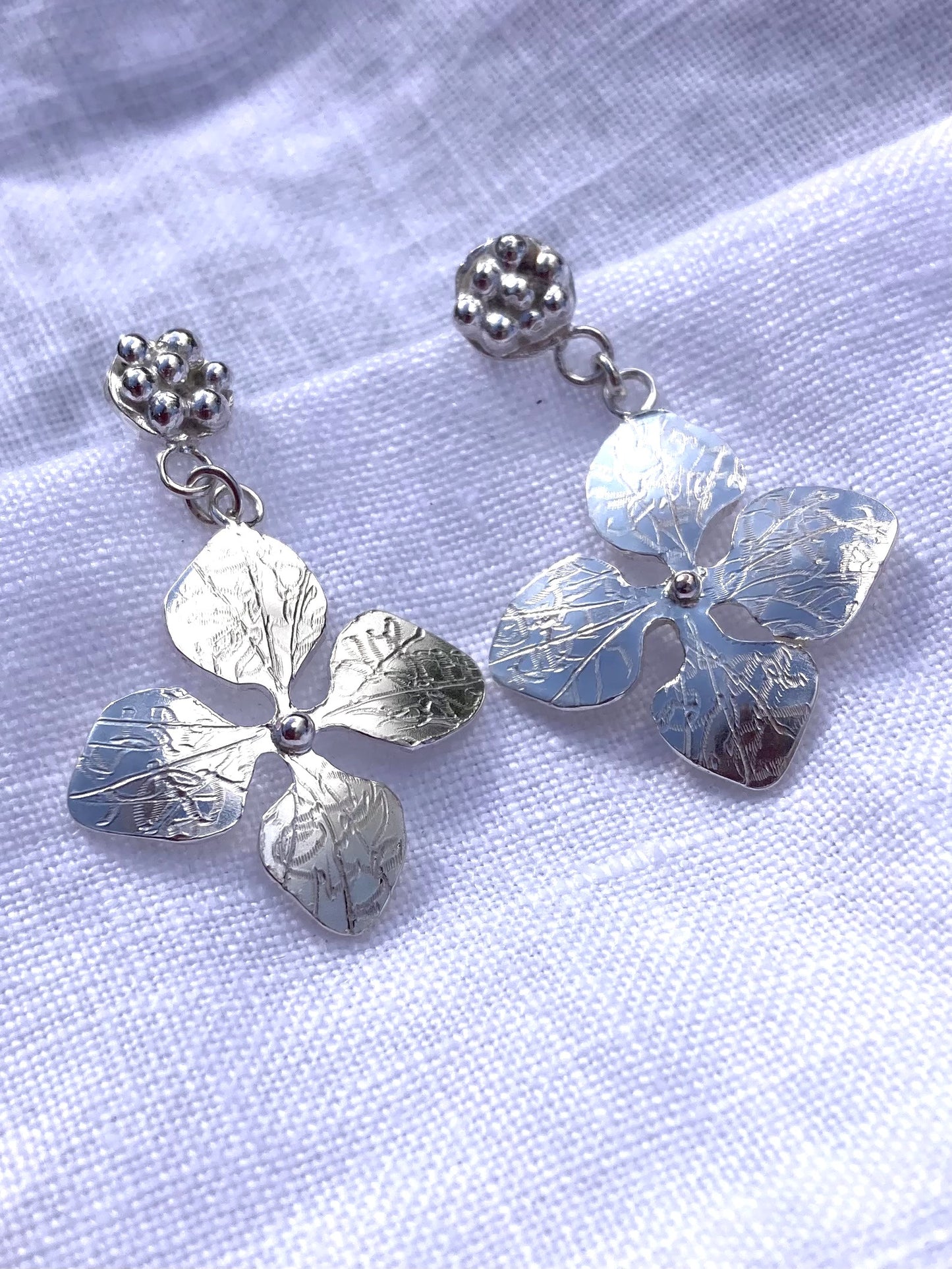 Hydrangea floral dangly earrings by Kim Styles on white linen background
