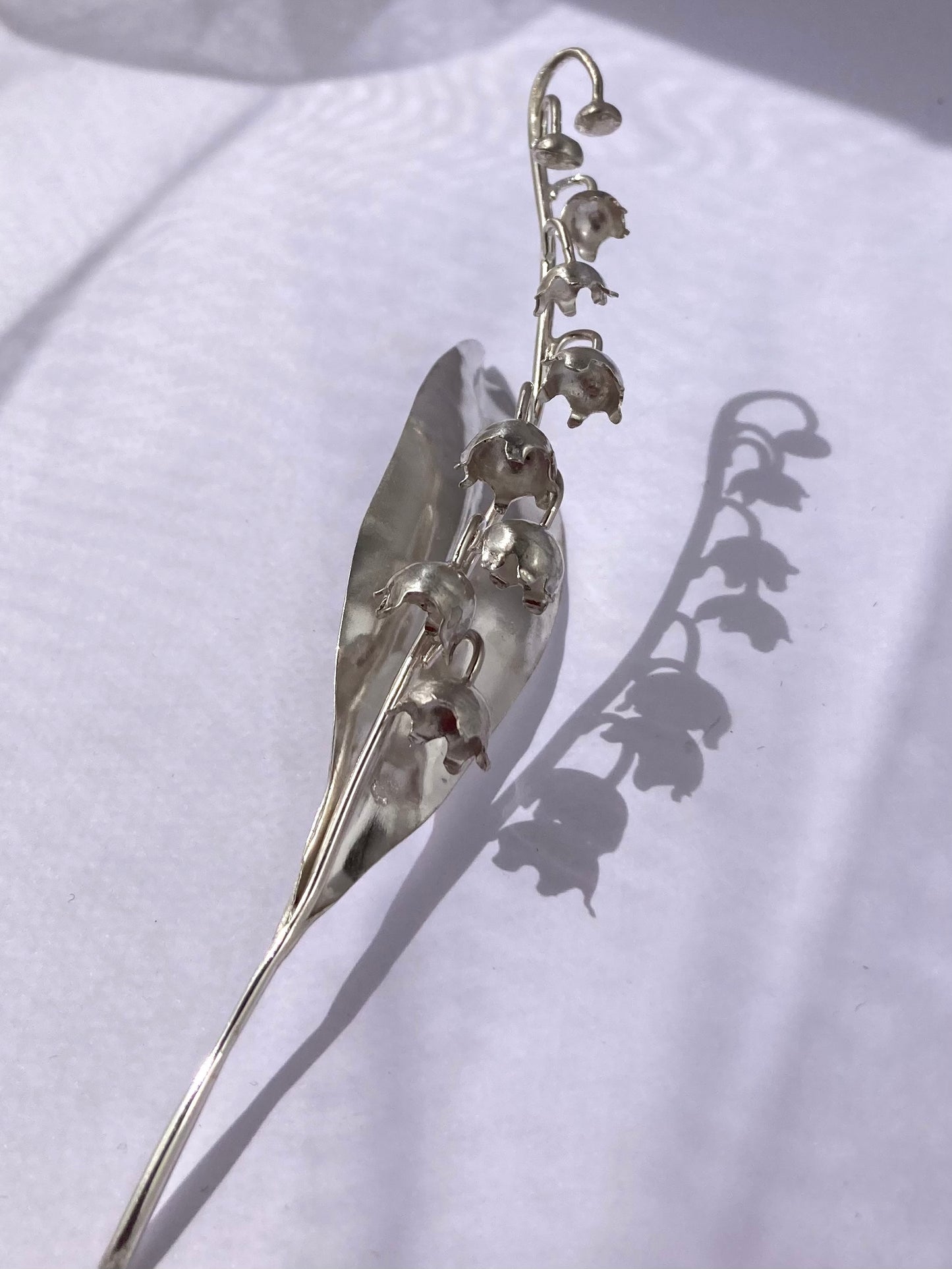 silver handmade lily of the valley sculpture and shadow