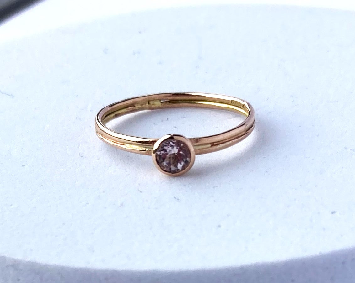 round pink gemstone set in rose gold twin shank ring, on white background