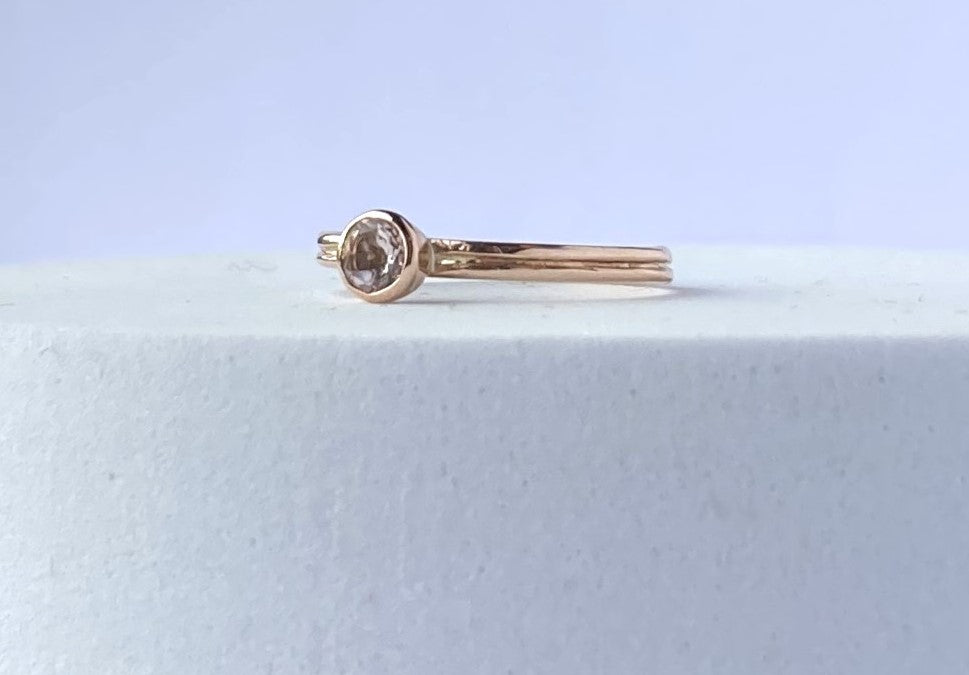 morganite and rose gold solitaire engagement ring, laying on white plinth
