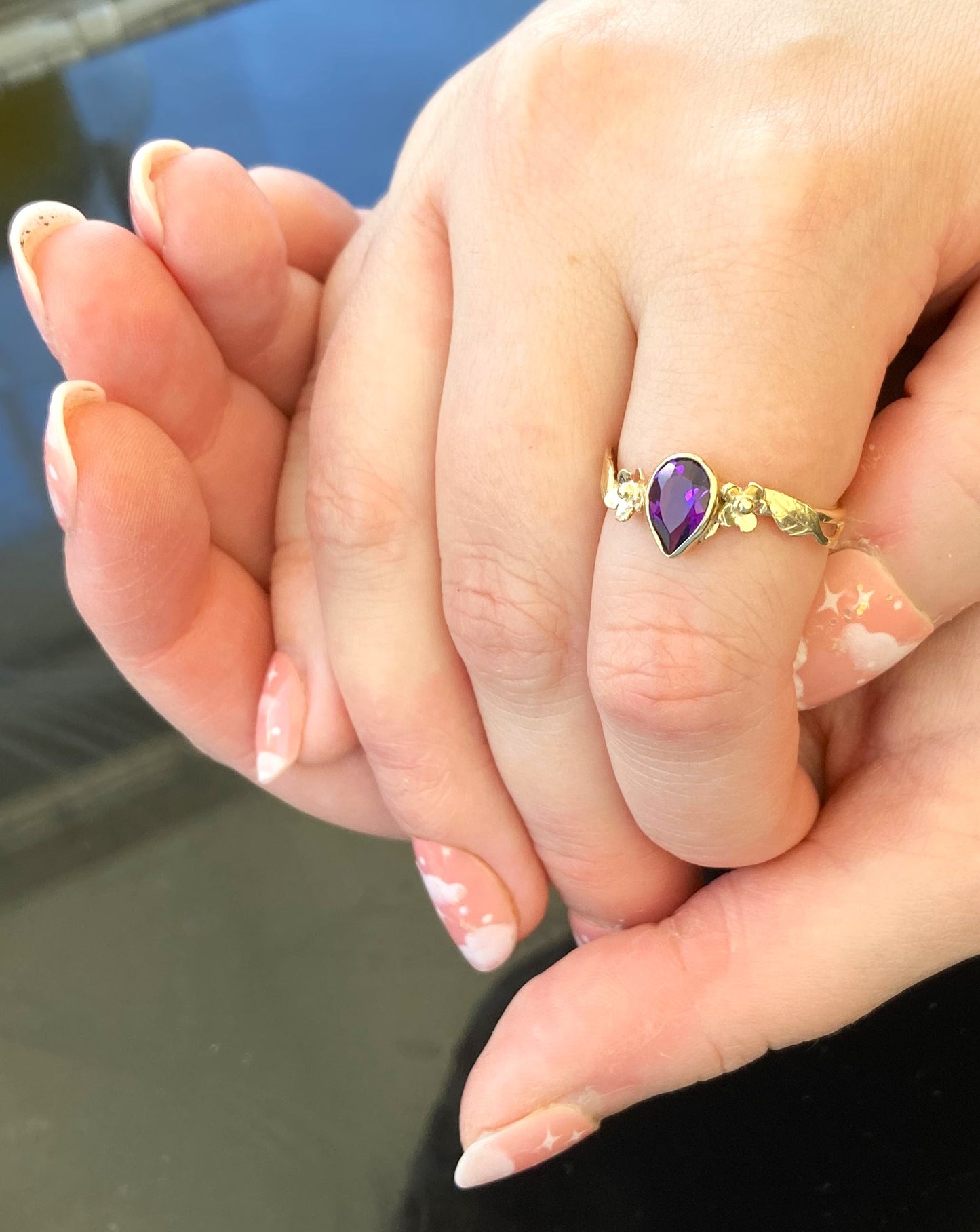 Gold floral ring set with pear shape dark amethyst, alternative engagement ring, worn on cupped hands