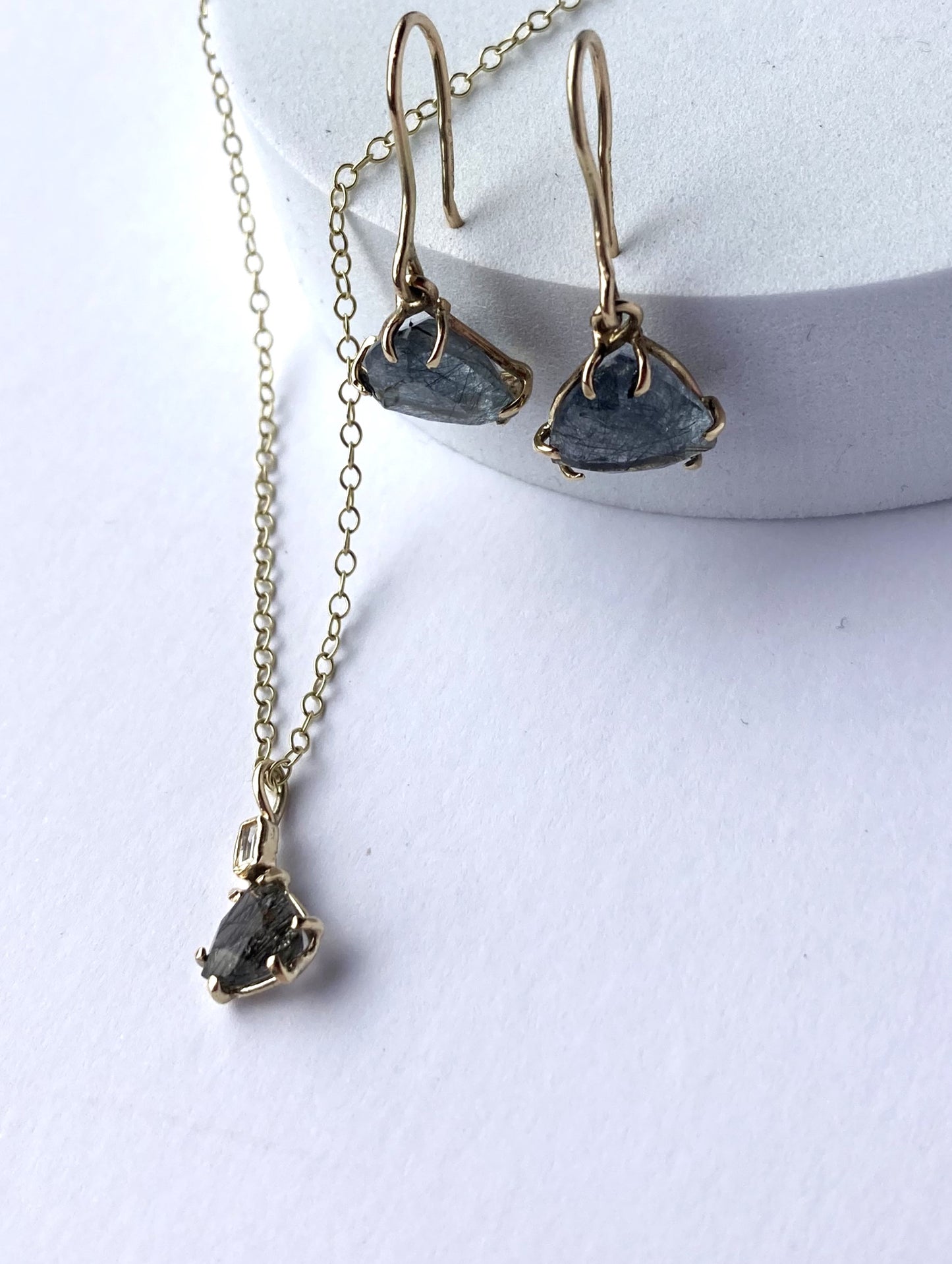 trillion cut rutilated quartz earrings and pendant in gold, on a white background