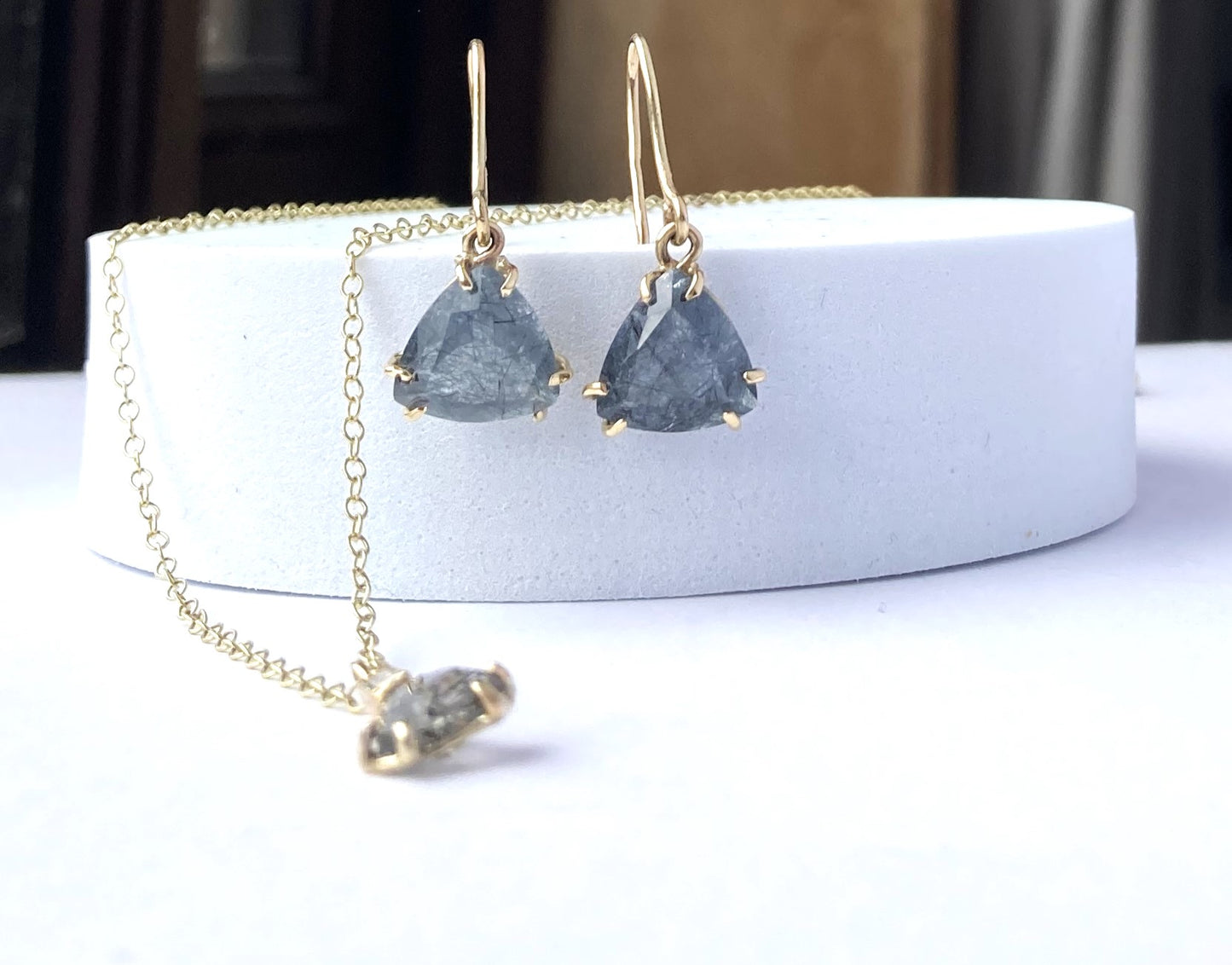 triangle rutilated quartz gold earrings and pendant, on white plinth