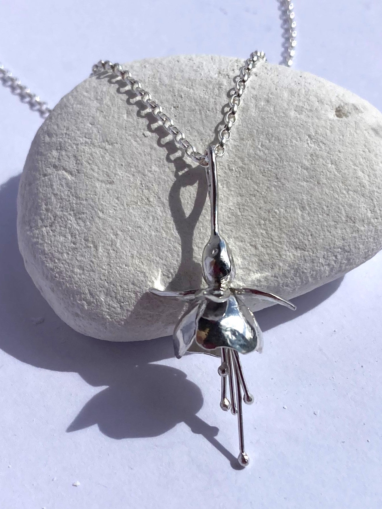 silver Fuchsia pendant on white pebble