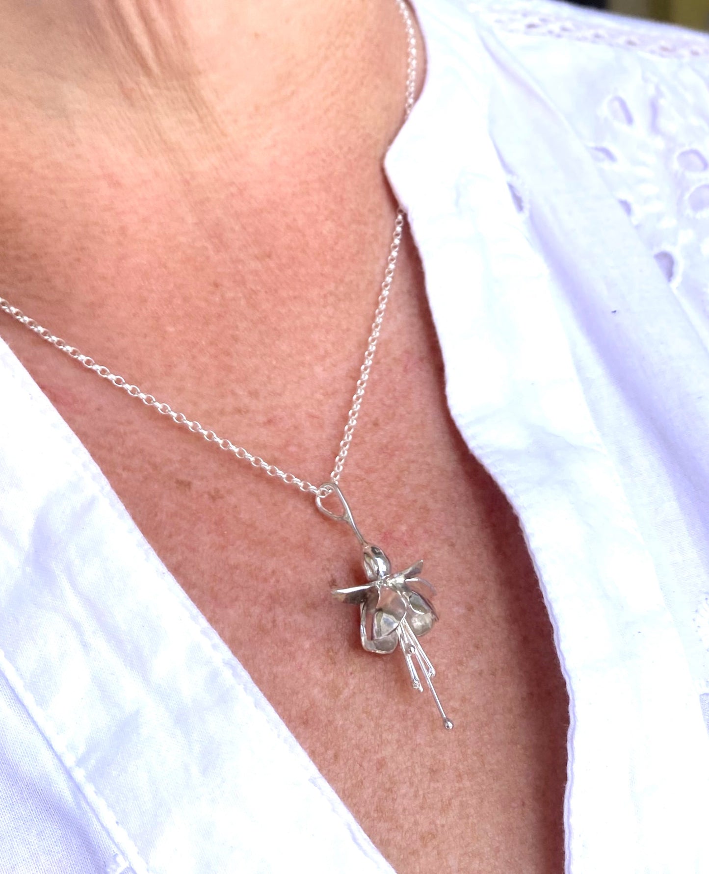 silver fuchsia pendant on neck with white shirt