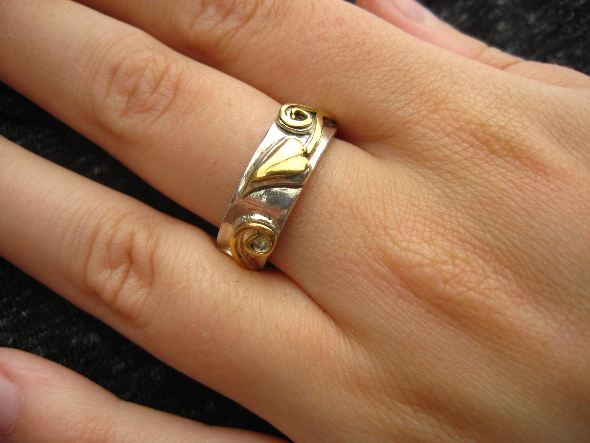 white gold wedding ring with yellow gold decorative raised details, on hand