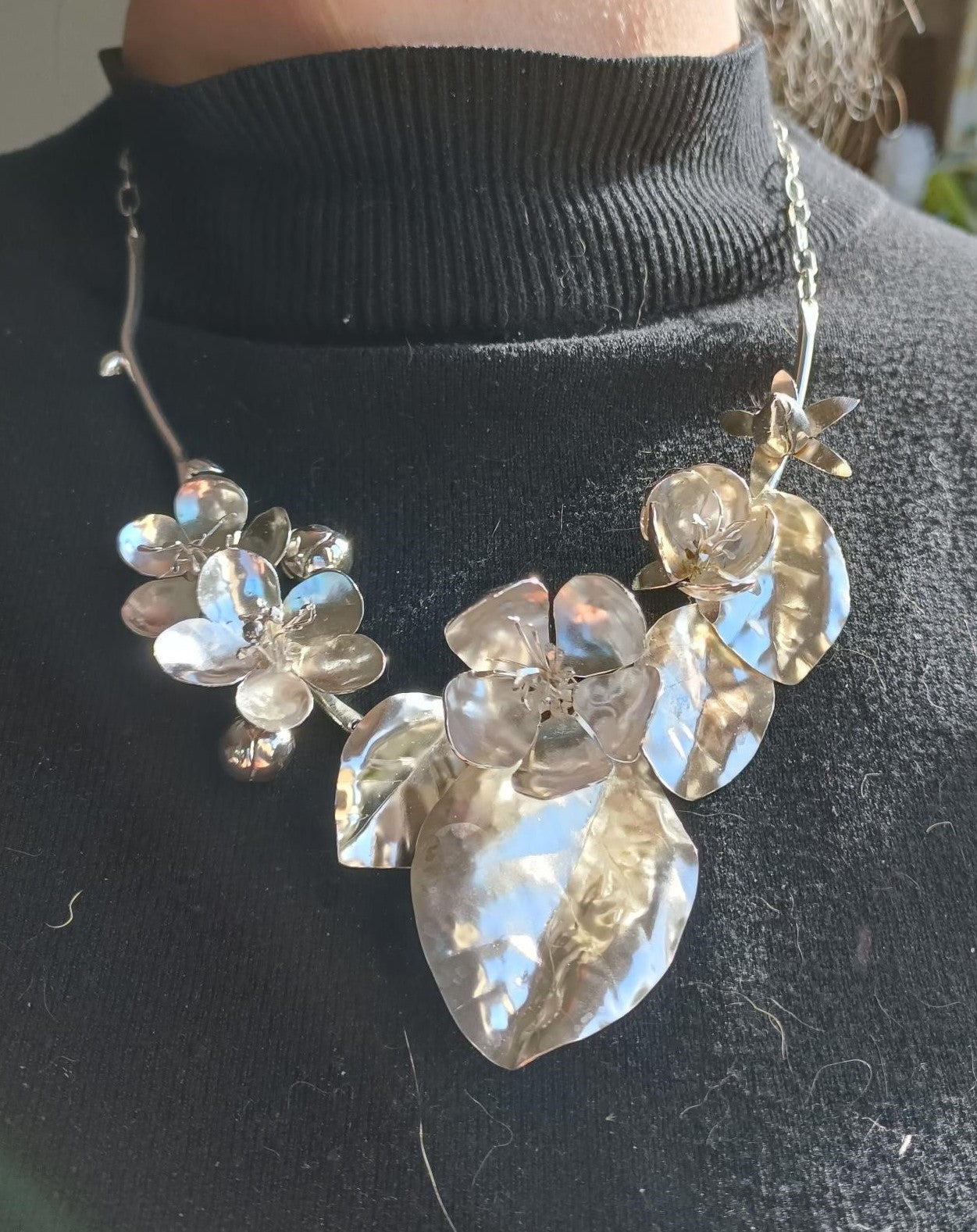 silver botanical floral necklace on black jumper