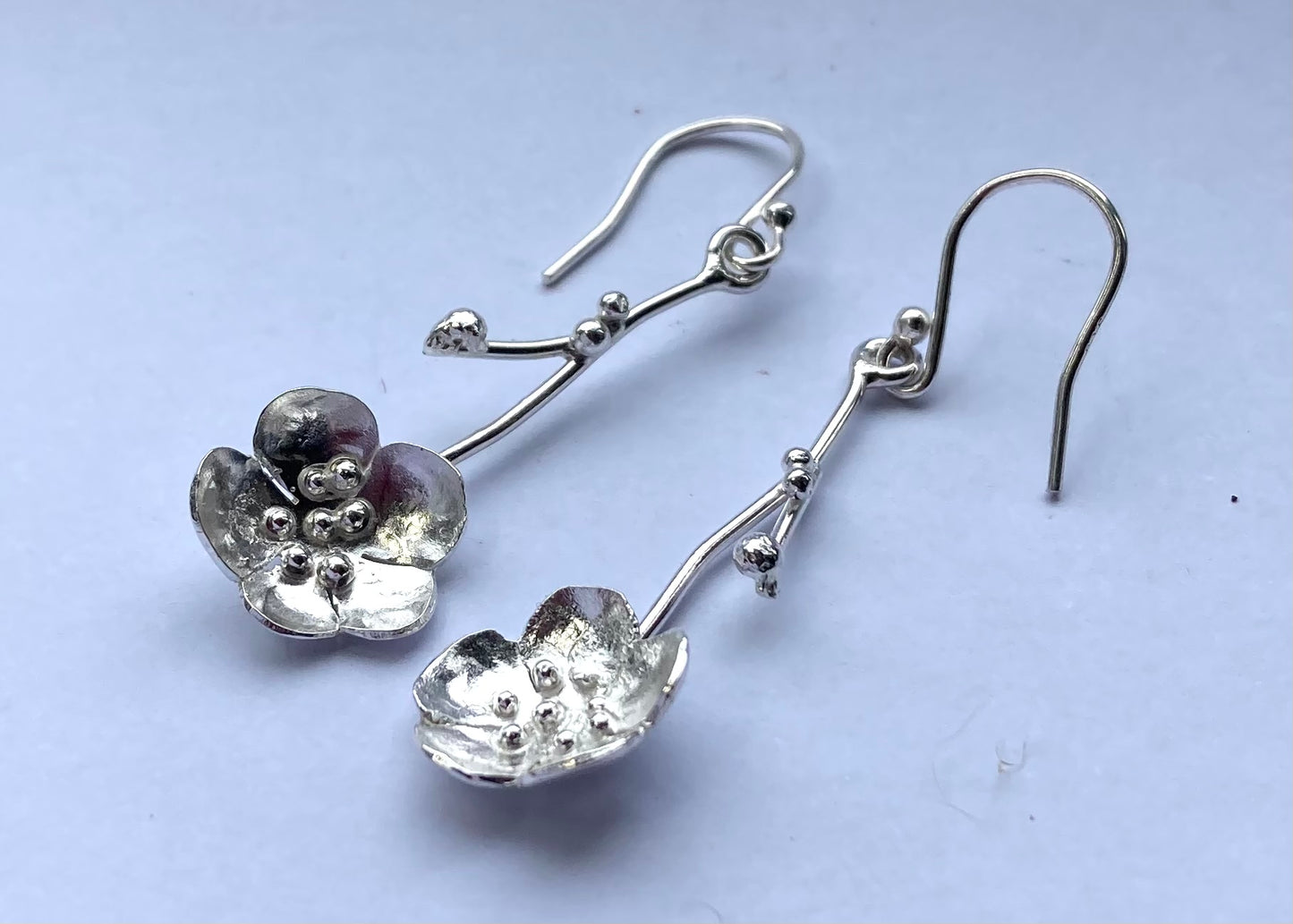 sterling silver hand fabricated cherry blossom flower hook earrings, on grey background
