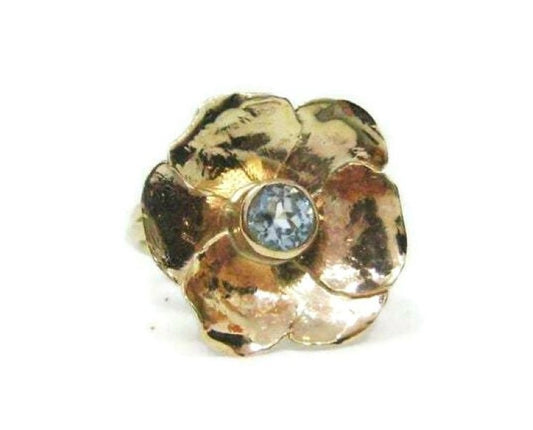 single yellow gold flower cocktail ring set with round blue topaz, on white background