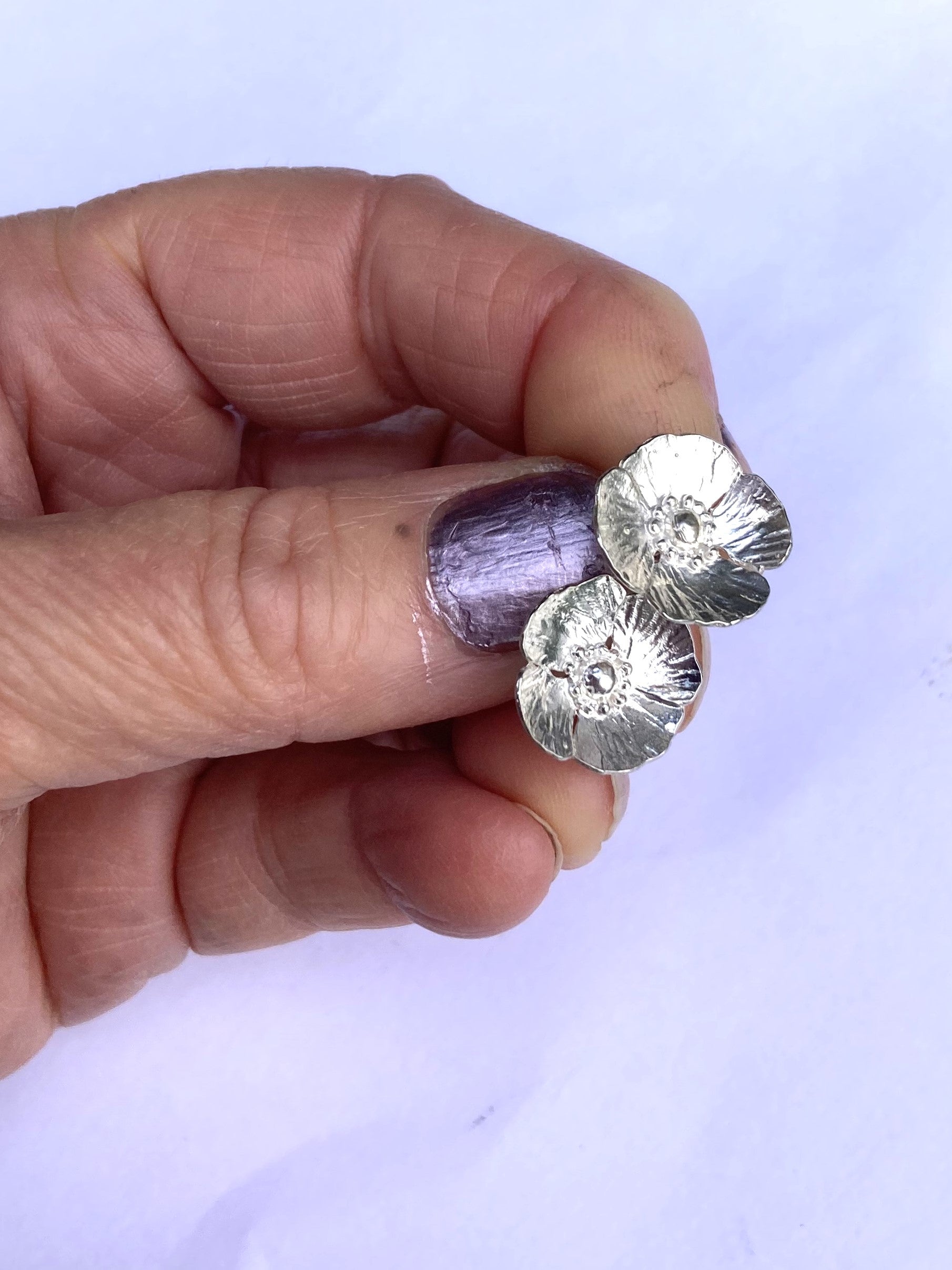 hand holding poppy stud silver earrings
