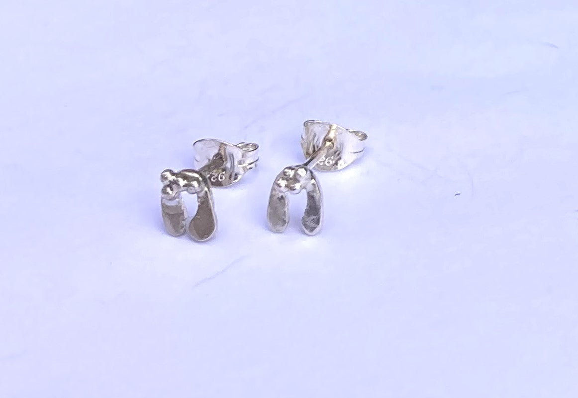 tiny handmade silver mistletoe leaf stud earrings on grey background