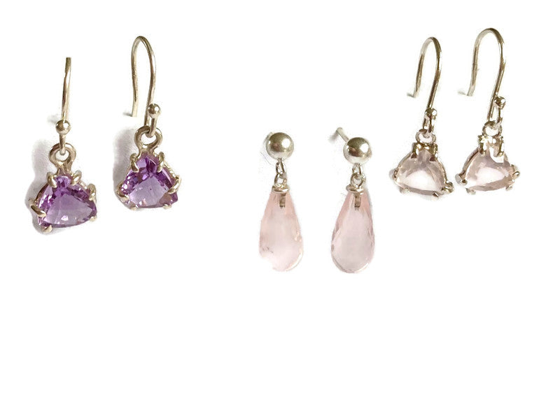 Set of silver earrings with purple and pink gemstones on a white background