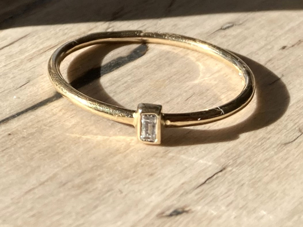Diamond baguette halo solitaire ring on wood texture