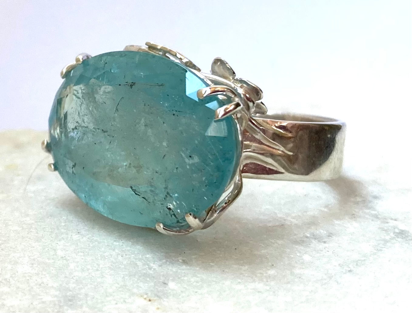 oval blue aquamarine with natural inclusions, in dual prong setting ring