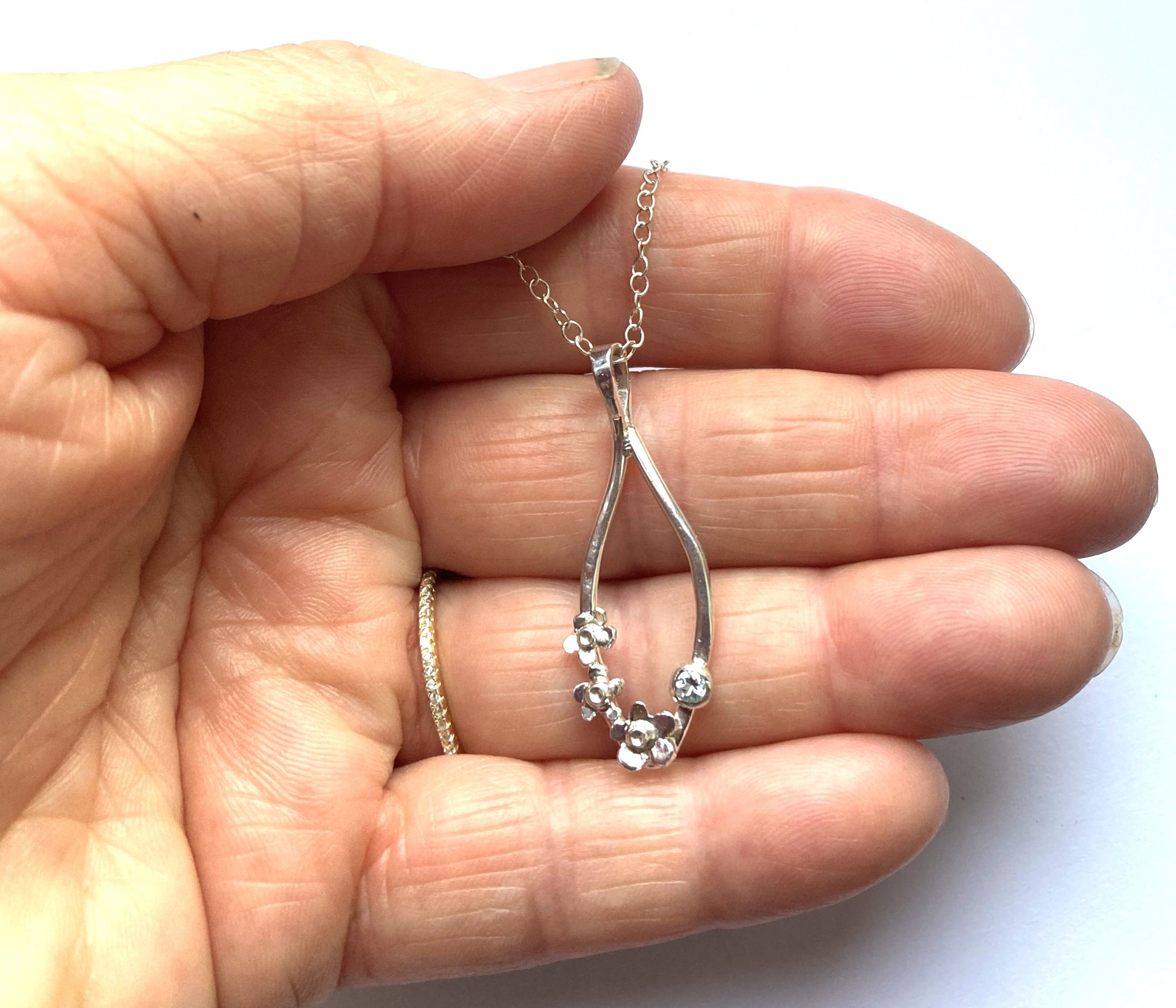 hand holding silver chain and forget-me-not flower  drop pendant