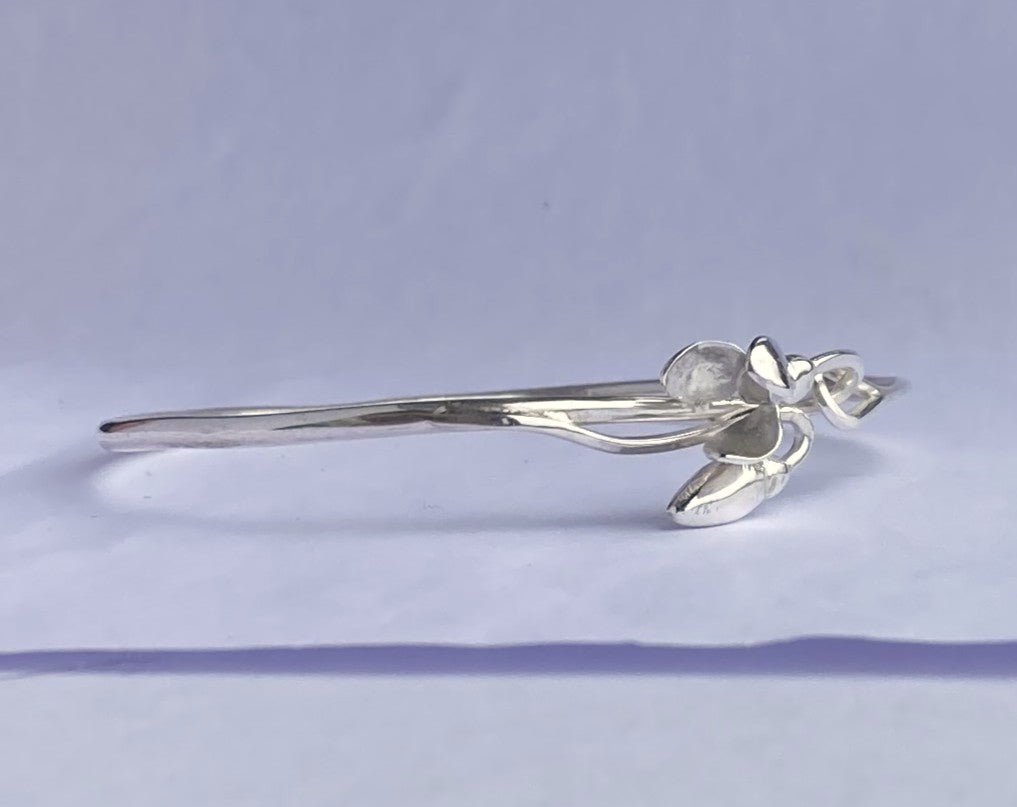 Hand forged 3D silver snowdrop bangle by Kim Styles Jewellery on a grey background