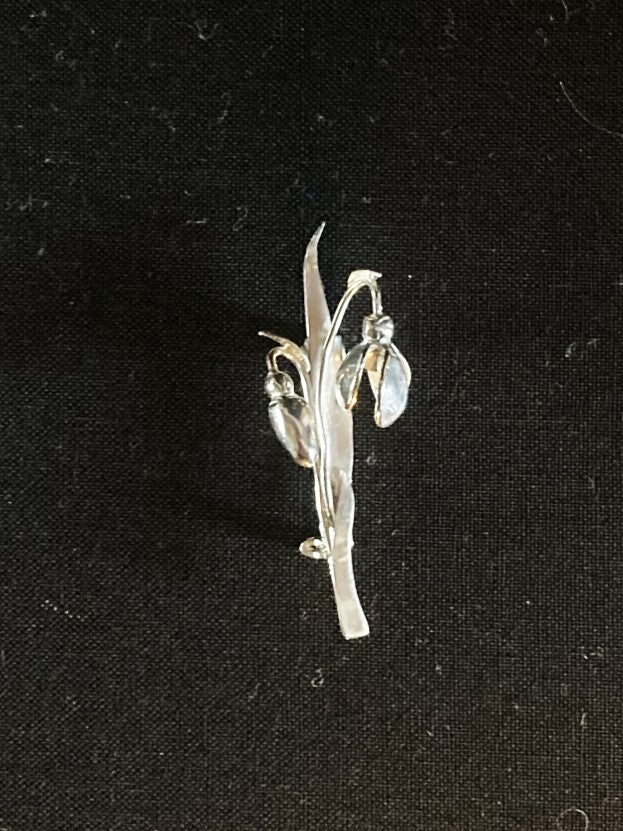 Silver brooch with floral design on a black background
