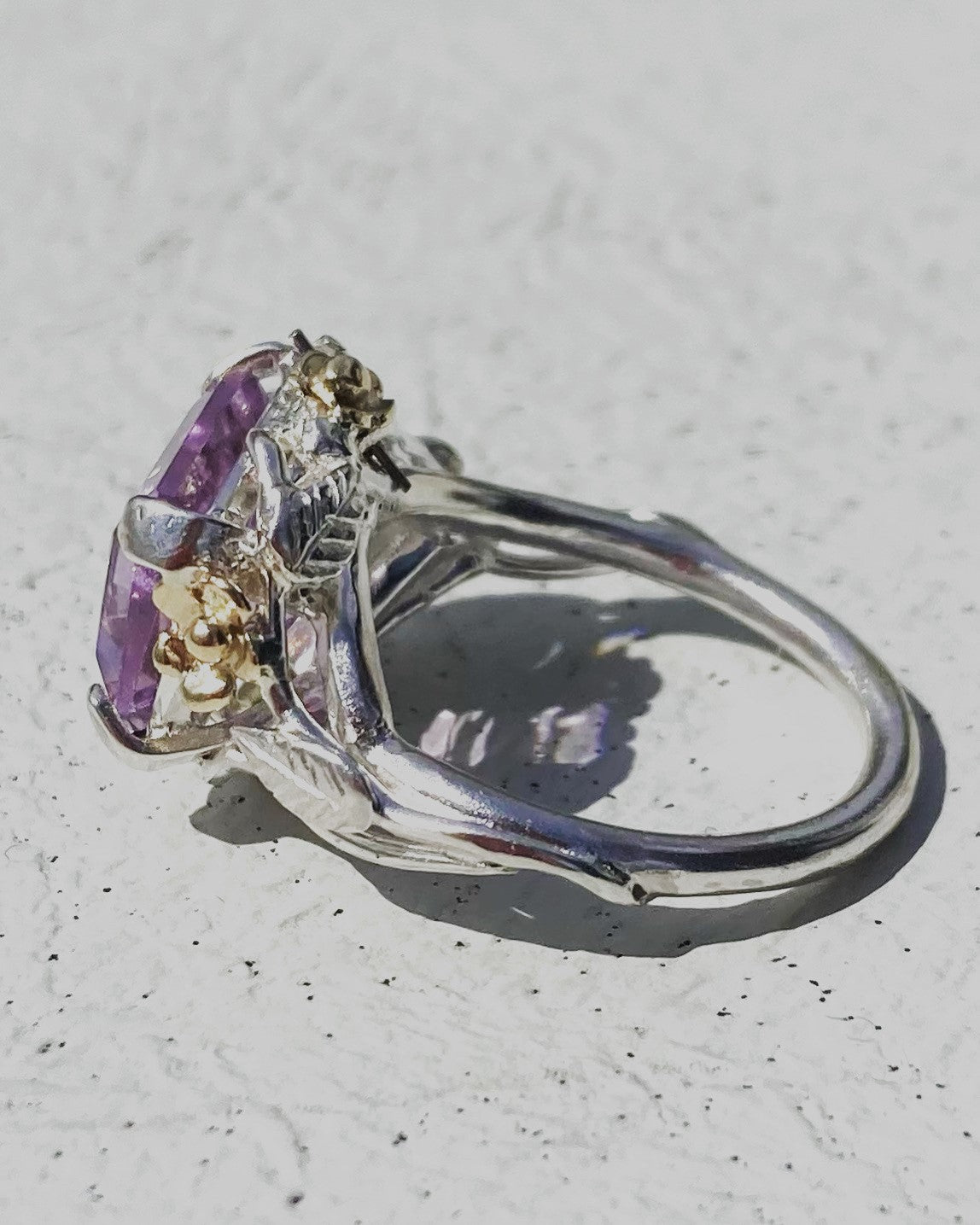 decorative amethyst cocktail ring with flowers and leaves detailing on grey background