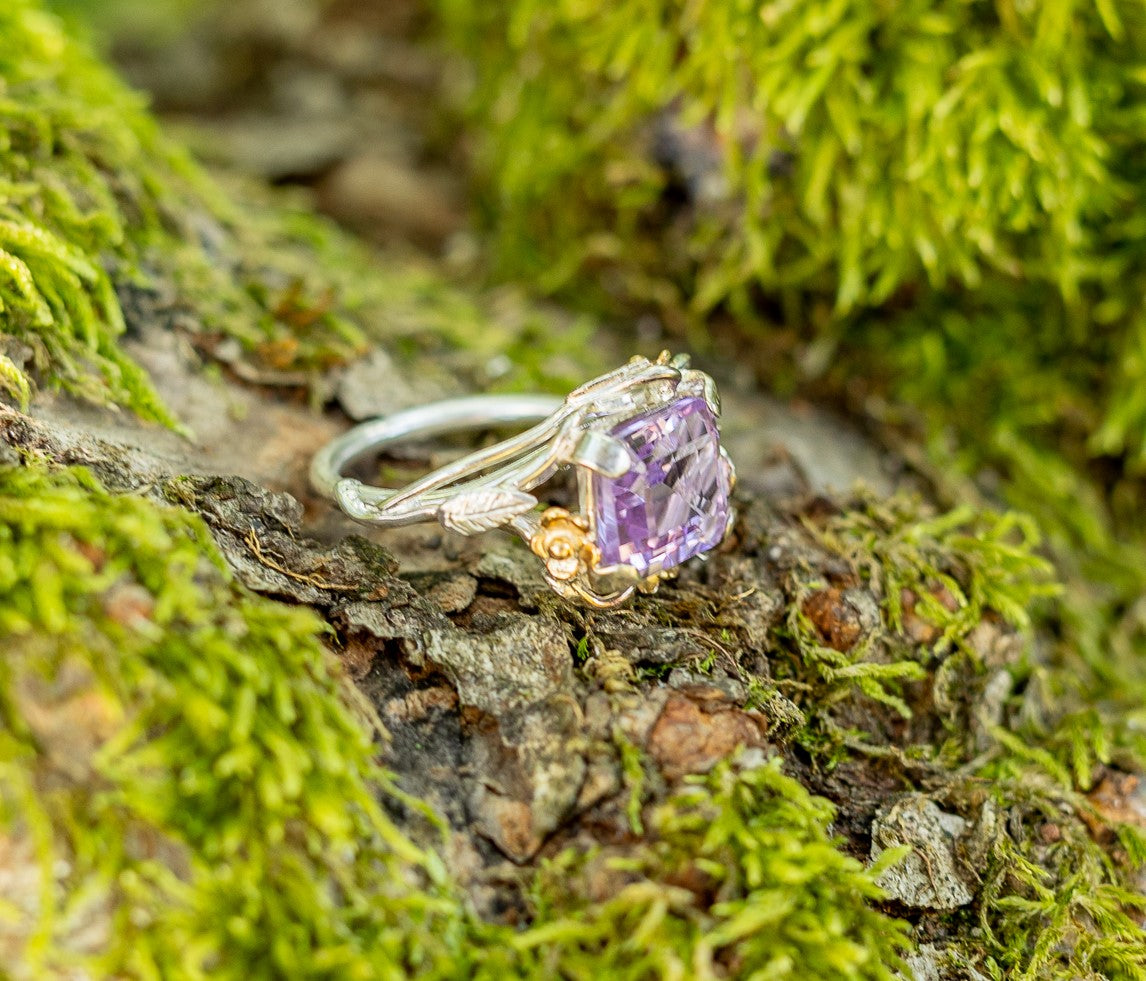 large amethyst gemstone ring with gold flowers on moss background