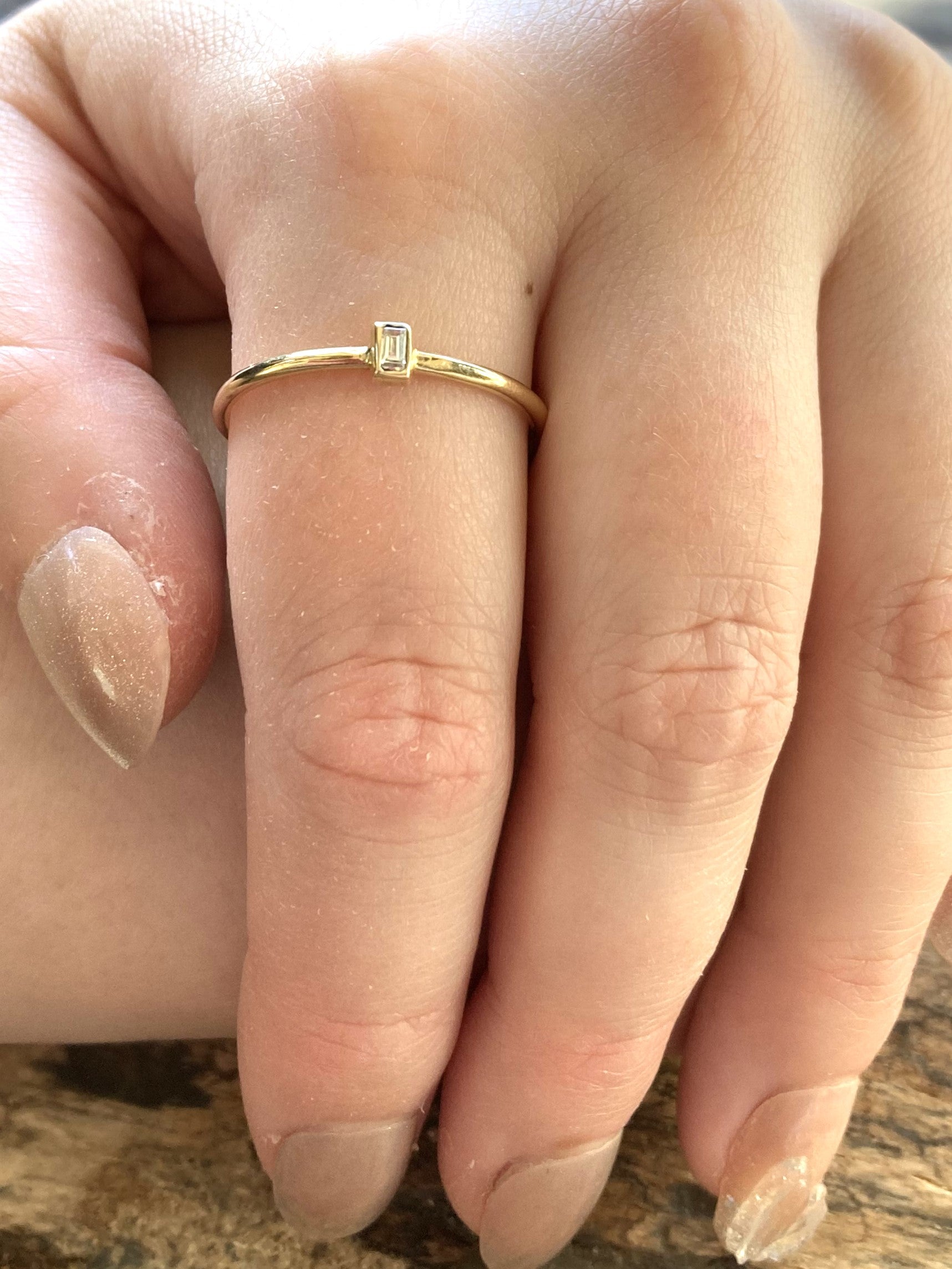 diamond baguette gold halo solitaire ring on ladies hand 
