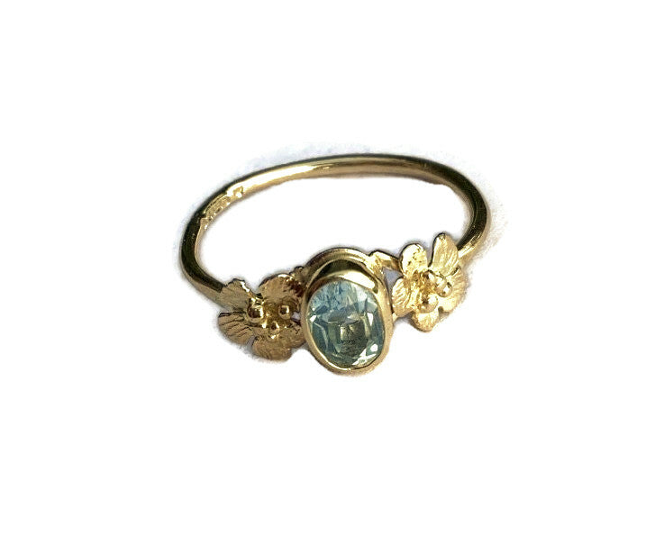 hallmarked gold ring with oval blue topaz gemstone and pretty yellow gold flowers