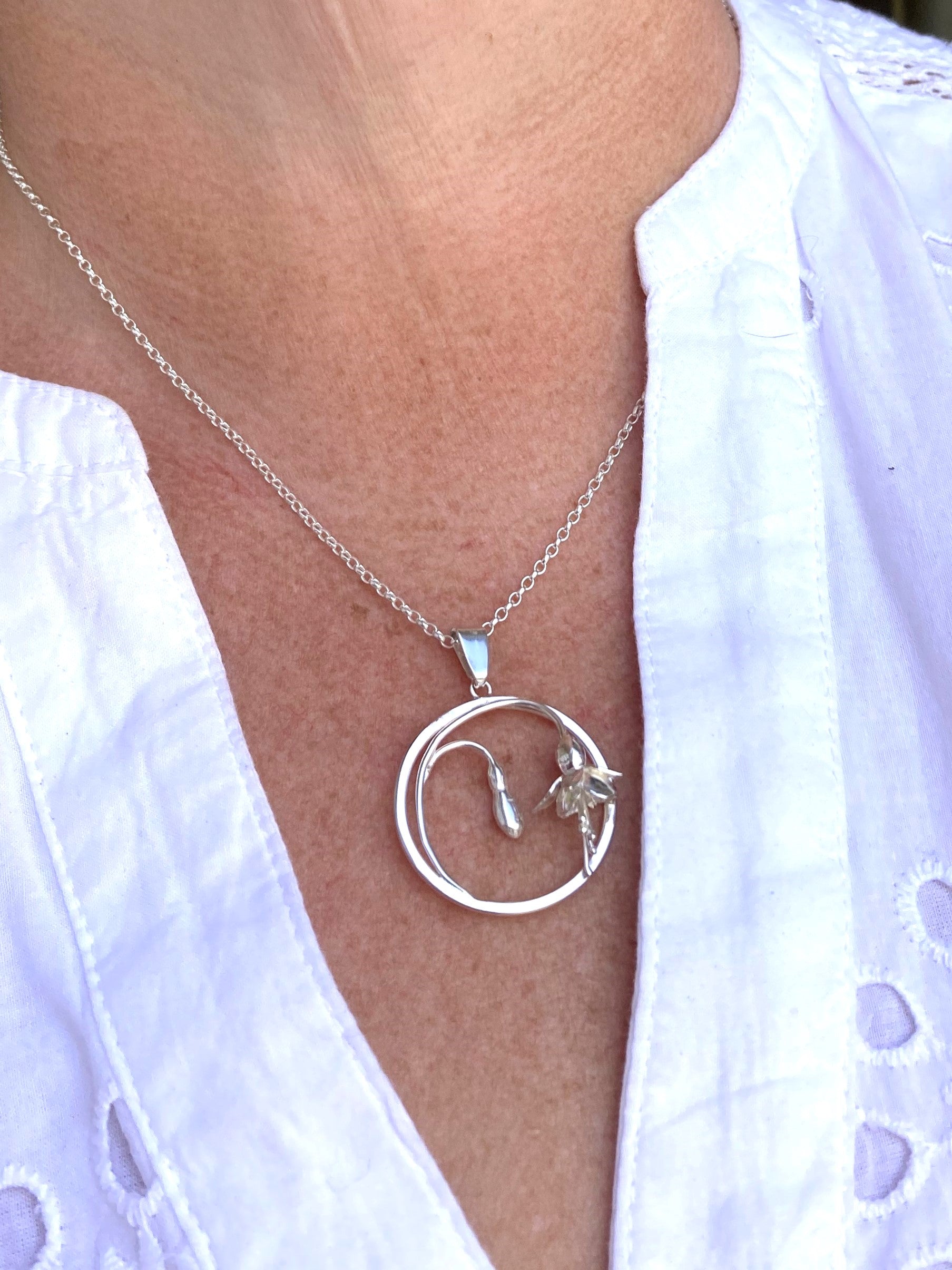 silver fuchsia pendant on neck with white shirt