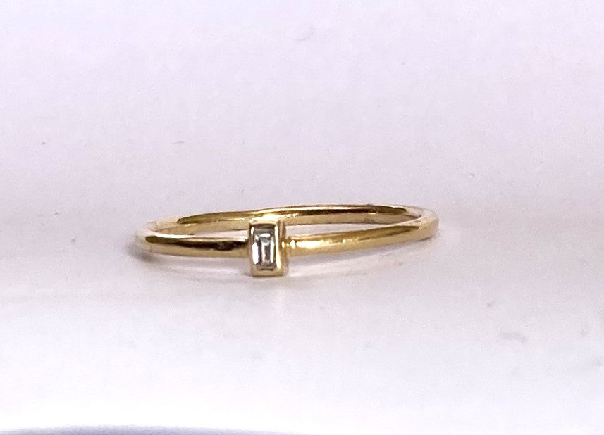 dainty diamond solitaire ring on white background