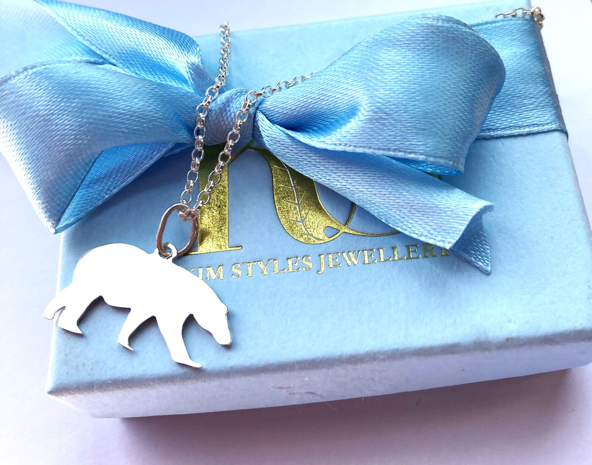 pale blue box with pale blue satin ribbon bow and silver handmade polar bear silhouette pendant resting on box