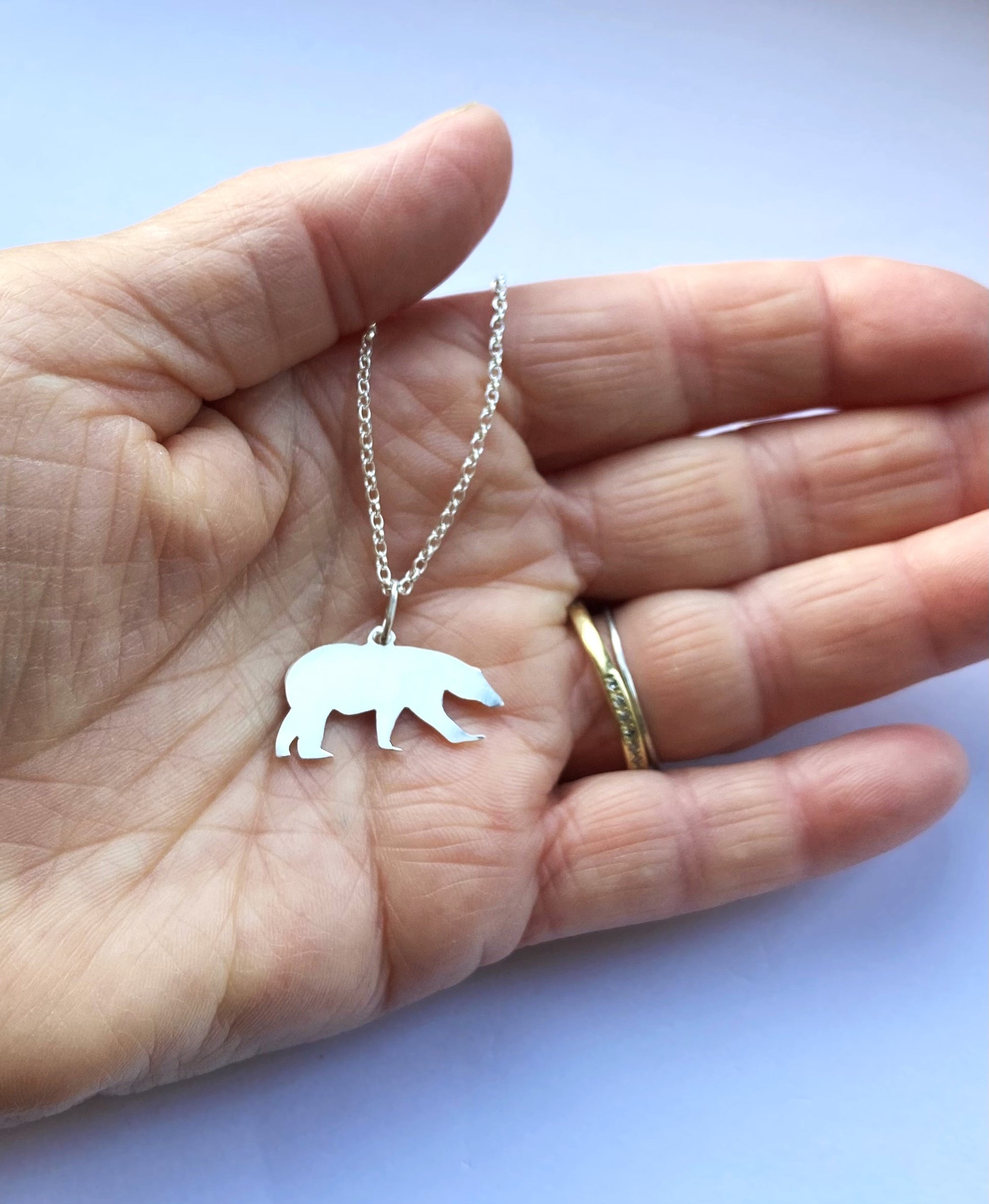 hand holding silver polar bear silhouette pendant