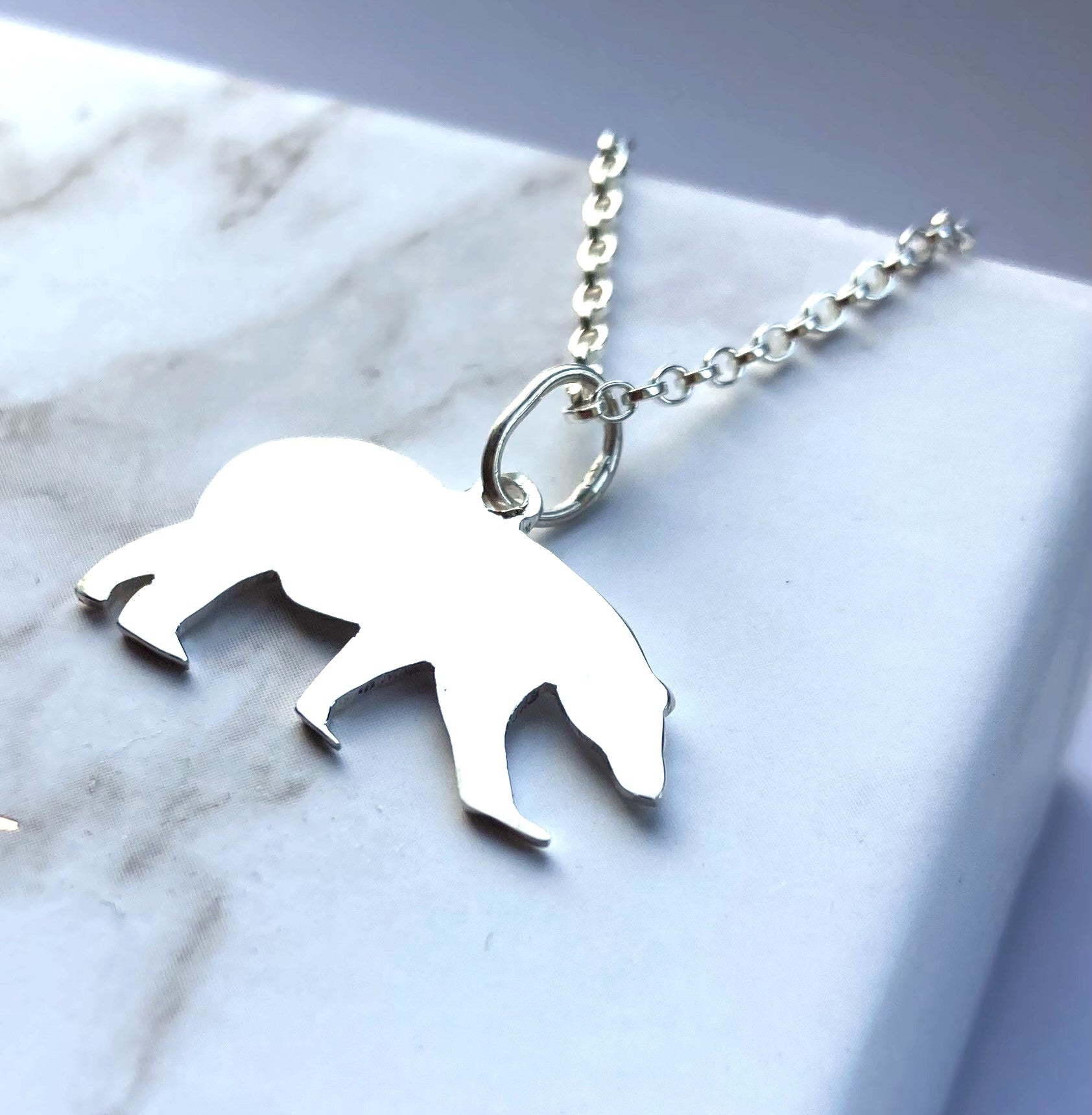 Polar bear silver pendant and chain on marbled background