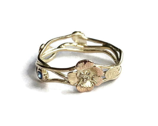 gold wire twisted ring with leaves and flowers on a white background