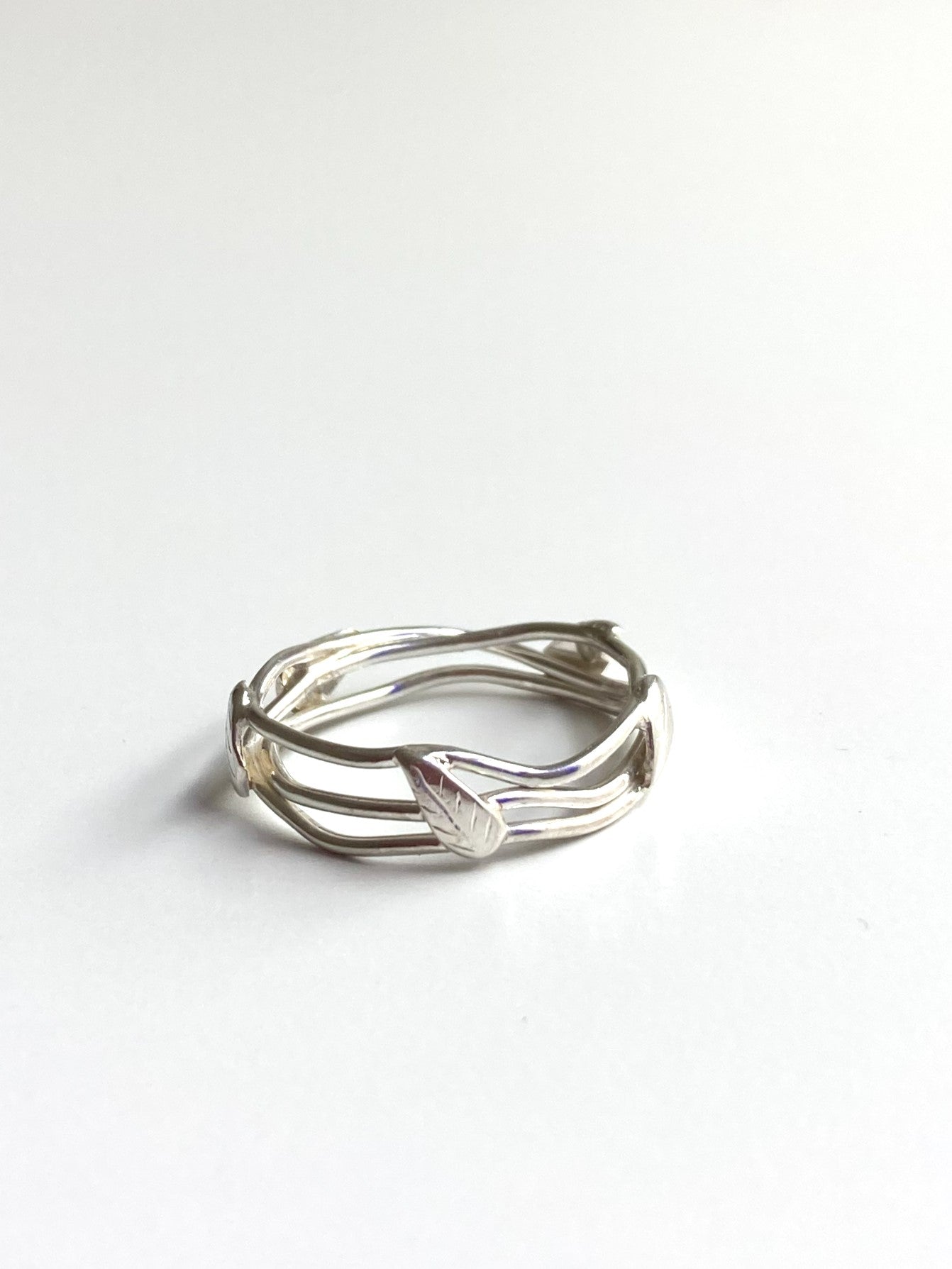 silver wire ring decorated with leaf detail, white background