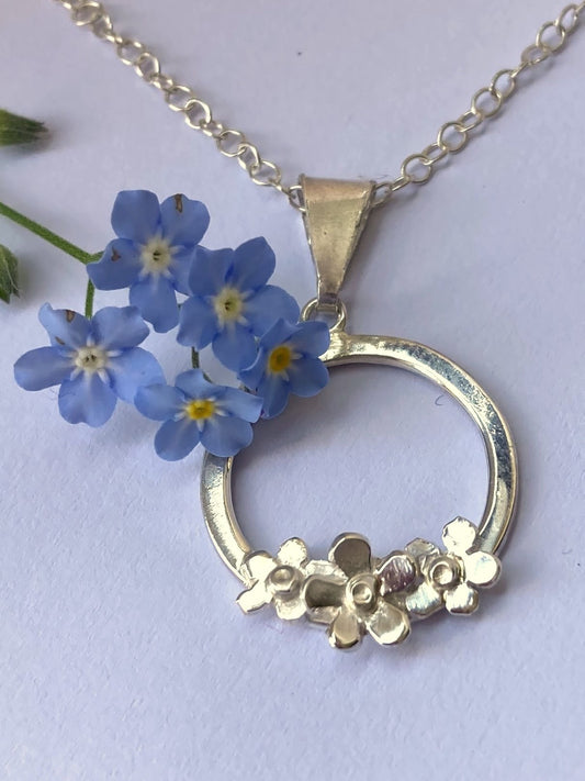 real blue forget-me-not sprig and silver circle pendnat with three silver forget-me-not flowers