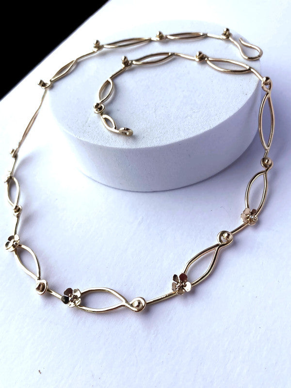 decorative link gold chain curling around a white round raised block