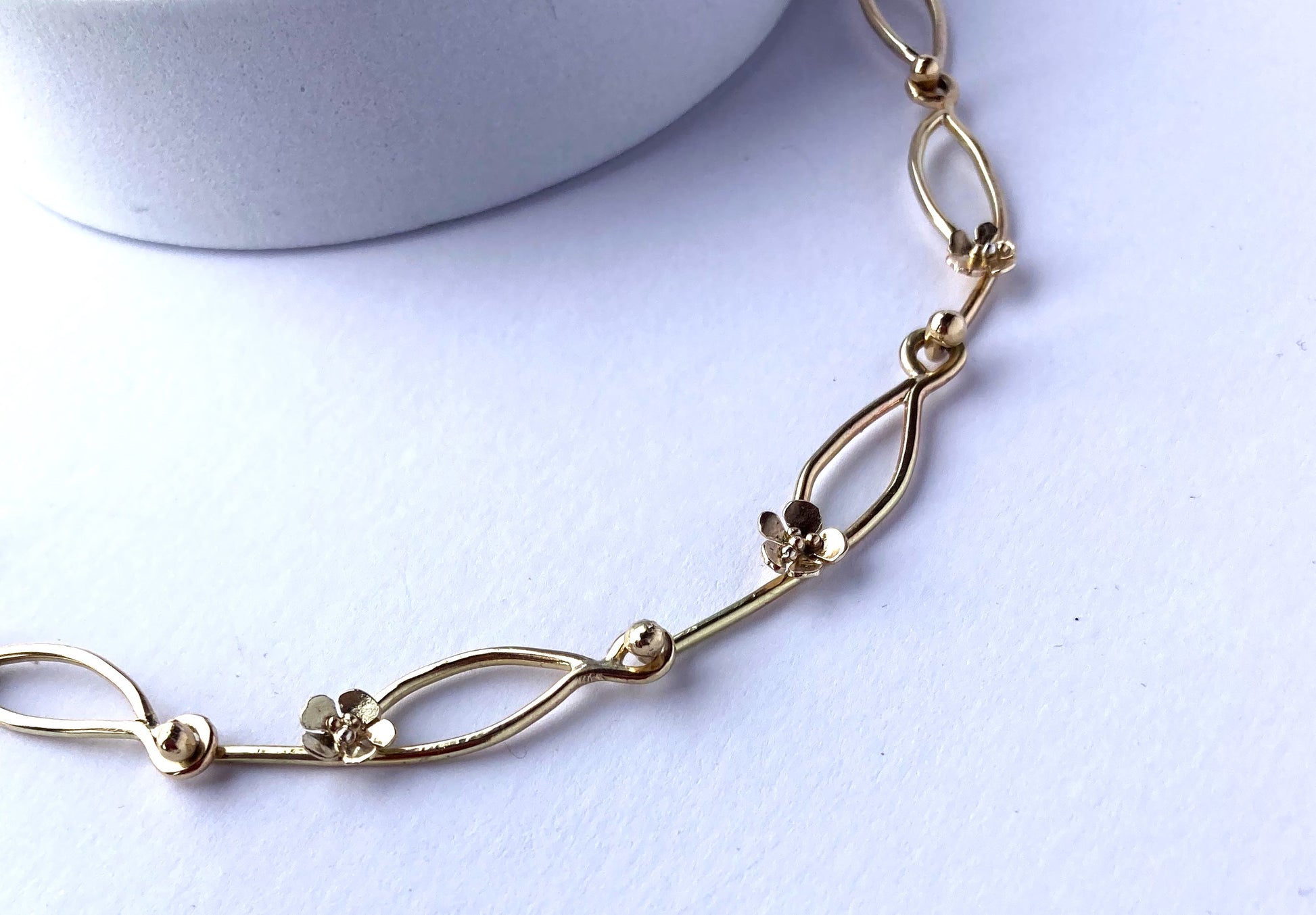 floral handmade gold chain on grey background