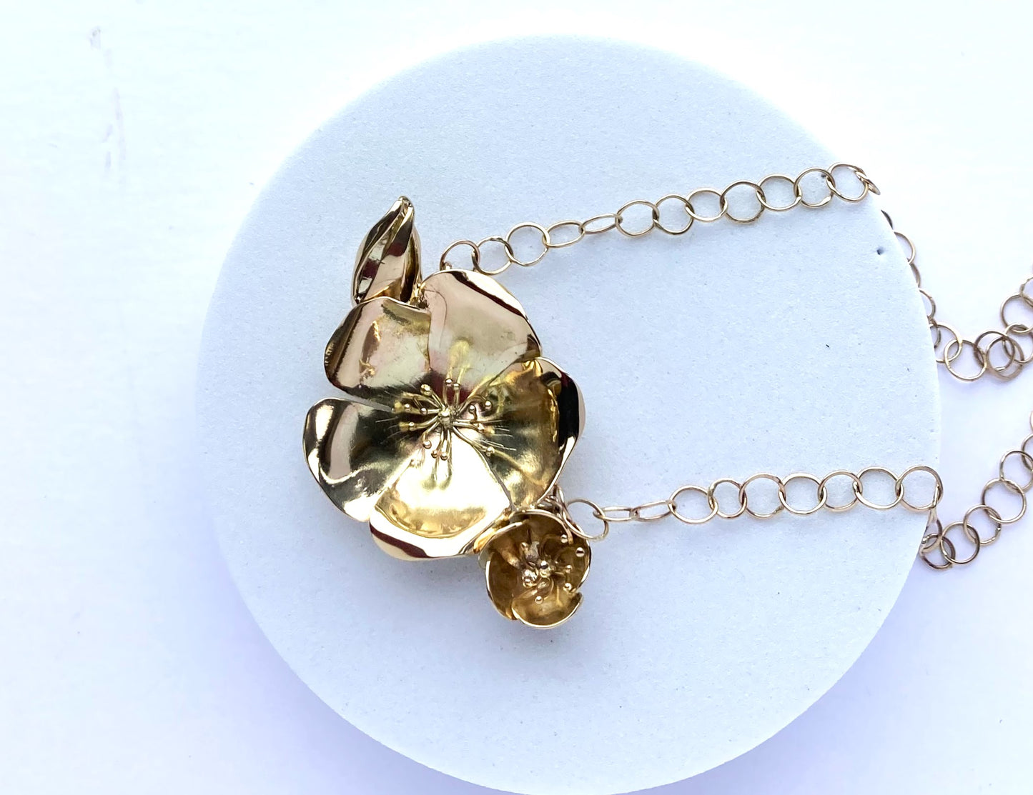 large gold floral necklace handmade by Kim-Styles-Jewellery, on grey plinth