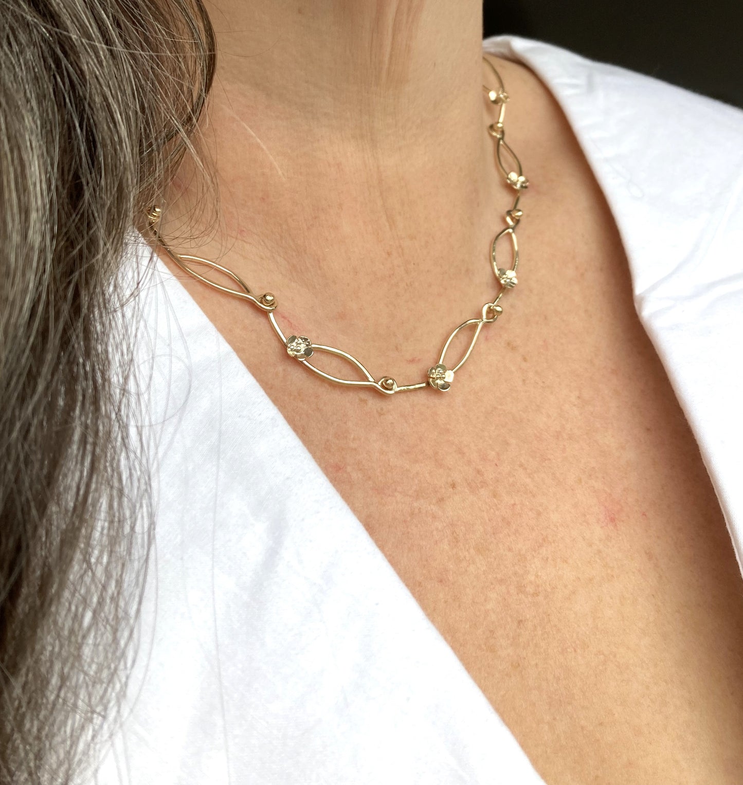 handmade gold floral chain necklace on neck with white blouse 