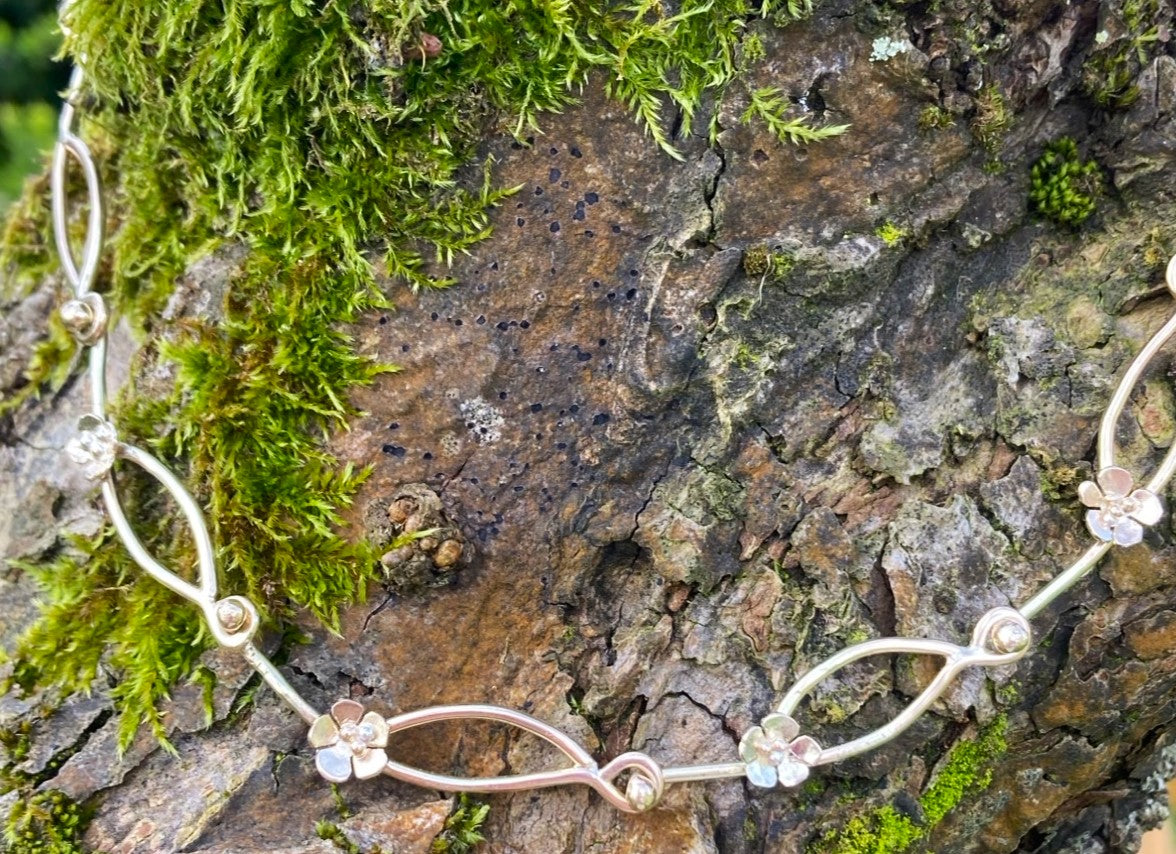 handmade gold chain with flower details on tree bark